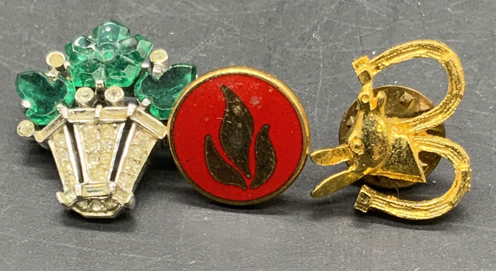 3 Vntg Bouquet, Flame, & Western Brooches, Trifari+: Three vintage brooches. A crystal floral bouquet brooch signed TRIFARI, PAT PEND to reverse alongside metal pin closure. A red enamel flame motif pin. And, a western motif brooch featuring a donkey &