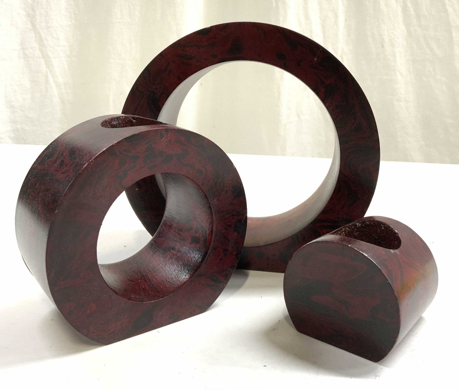 Set 3 Wood Nesting Candle Holders Red: Set includes 3 candle holders. Each are red & black toned, appear to be wooden, possibly mock wood. Candle holders nest and fit inside one another. Largest piece measures approximately 6.75 inches tal