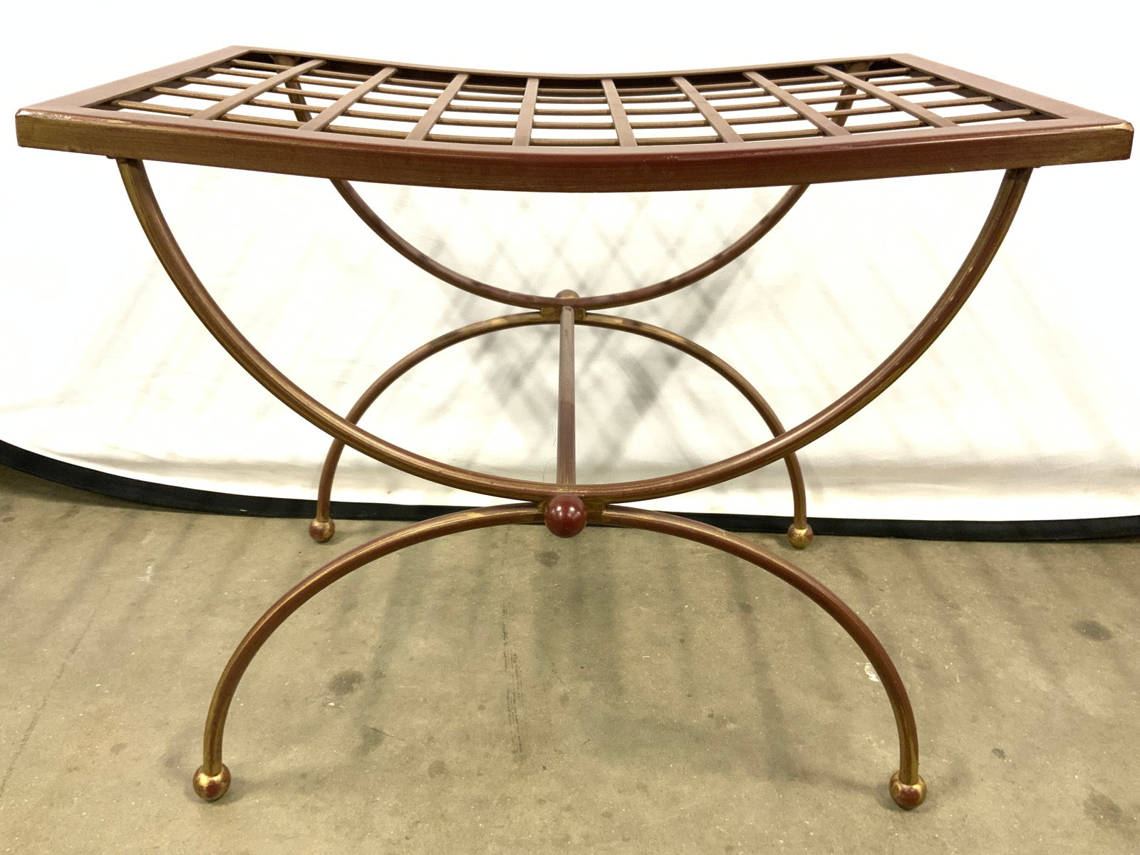 Outdoor Metal Curved X Bench: Bench is metal, possibly iron. Piece has gridded seating area. Bench has curved X form legs. Piece has 4 spherical form feet. Bench measures approximately 18 inches tall 13.5 inches deep 21 inches wid
