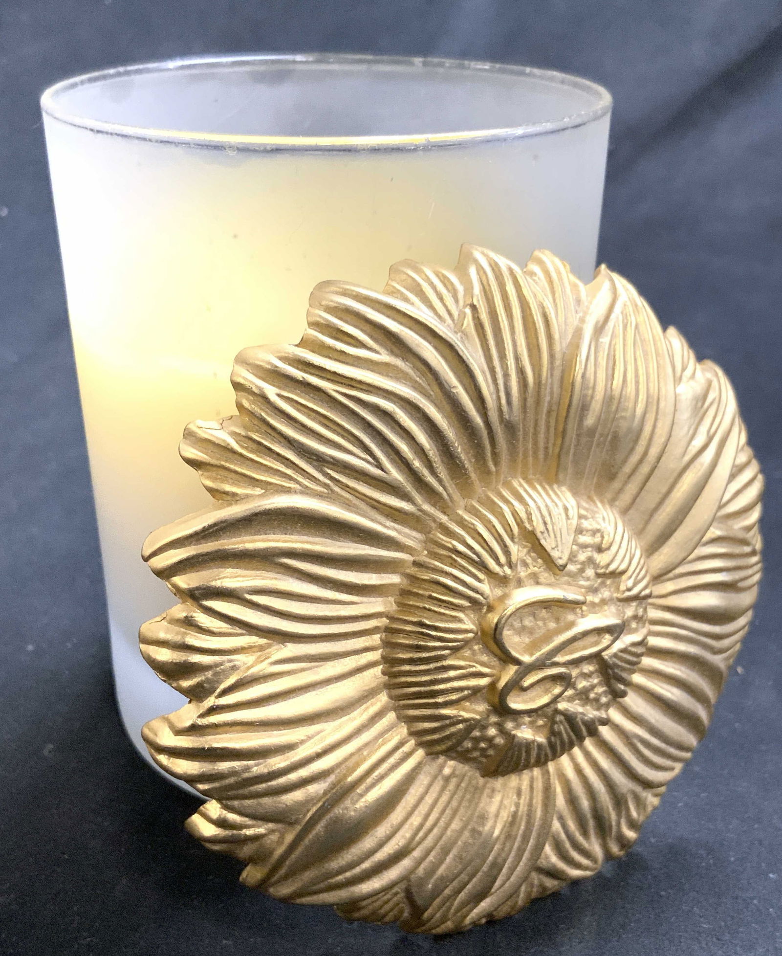 Chopard Glass Candle Holder & Gilt Metal Lid France: Chopard Candle holder is glass with cylindrical shape. Piece has gilt metal floral form lid with script letter C. Interior has cream toned candle. Piece measures approximately 4.5 inches tall 3.5 inch