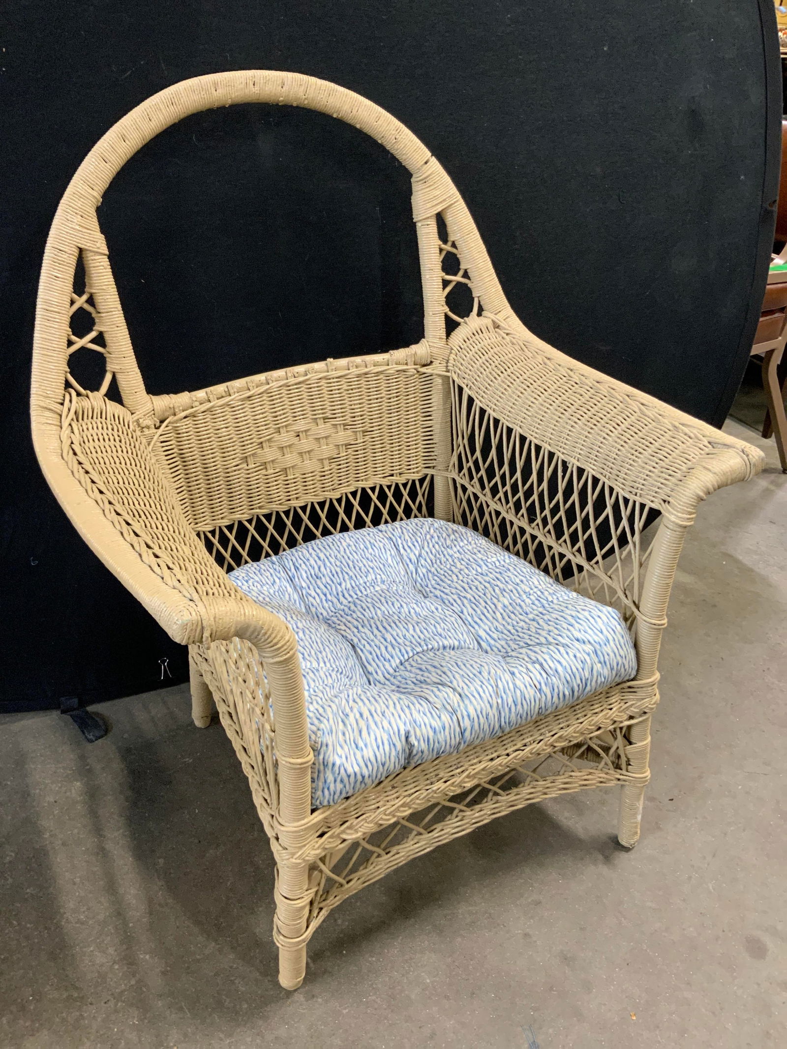 Vintage Woven Wicker Armchair W/ Cushion: A vintage woven wicker armchair with a removable cushion. Painted a beige hue. Measures approx. 39.5H x 28.5W x 20D in. Some wear consistent with age, use, and exposure. Some discoloration and losses