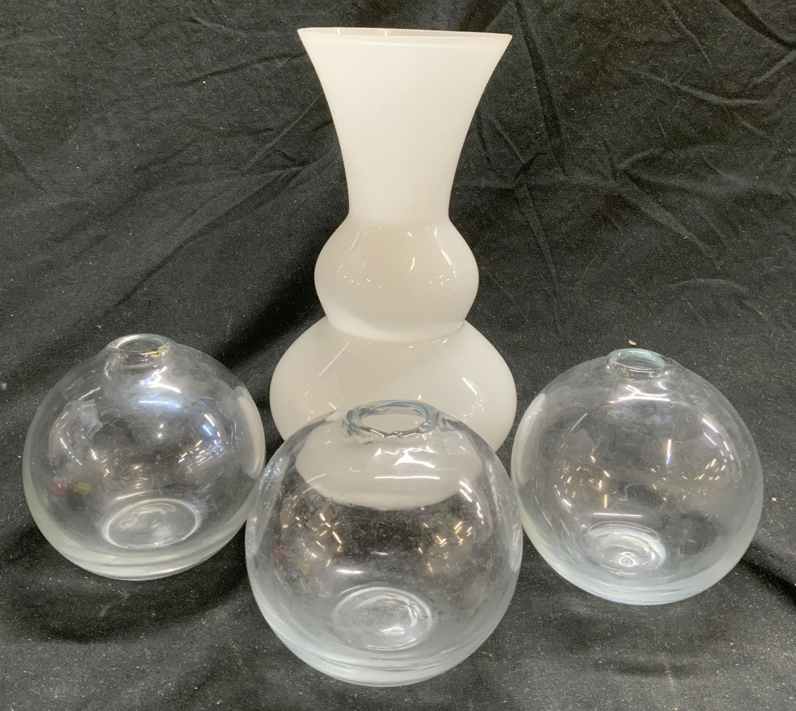 Lot 4 Art Glass Vases Vessels: Lot includes 1 milk glass vase & 3 spherical form vessels. Spherical form vessels appear to possibly be hand blown & each have narrow mouths. Neck of vase expands outwards towards top. Vase measures a