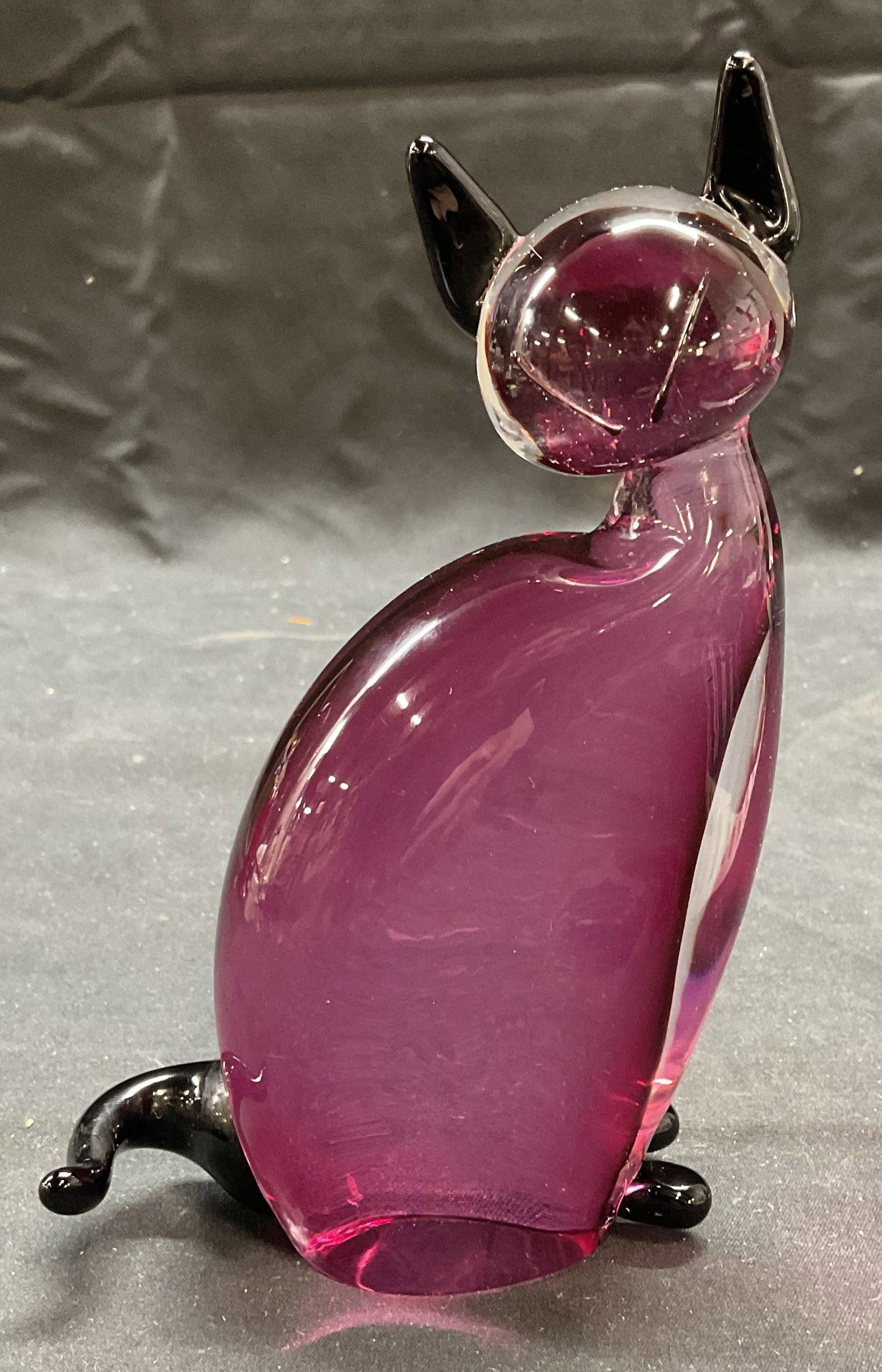 Hand Blown Purple Art Glass Cat Figural: Hand blown purple and black toned art glass cat figural. Measures approx 3.75 x 1.5 x 6.25 inches. Some surface wear consistent with exposure. Art glass, art glass cat, cat, cat figural, collectibles,
