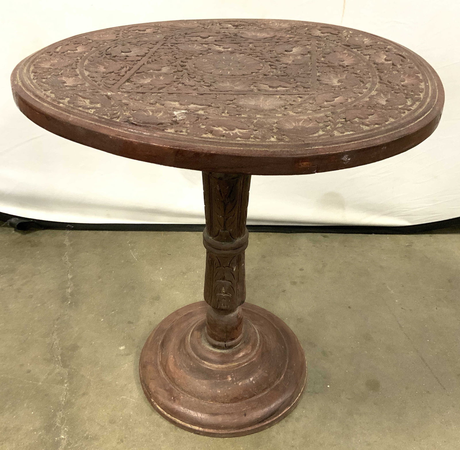 Moorish Vntg Carved Wooden Pedestal Table: Table is vintage. Piece is brown toned and wooden. Moorish pedestal table with intricately carved geometric & tribal relief detail Measures approx 22 inches tall 21 inches deep. Table, wooden table, v