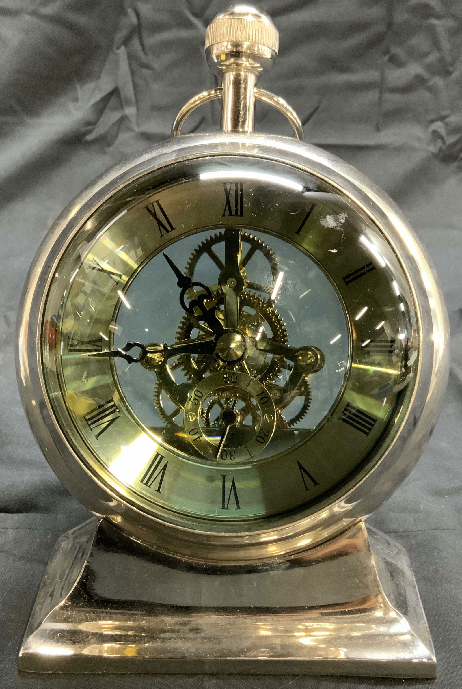 Shelf Marine Clock Bubble Gls Magnified Globe: Clock has metal and glass magnified globe. Front of glass magnifies clock face. Interior is black and gold toned with Roman numerals. Clock gears and inner workings are visible. Top of piece has metal
