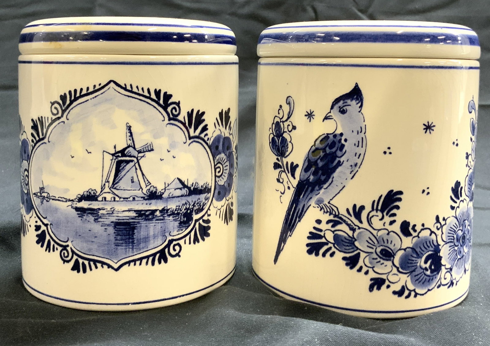 DELFTS BLAUW Lot 2 Porc Lidded Canisters HOLLAND: Undersides are marked DELFTS BLAUW HOLLAND HANDWERK. Lot Includes 2 jars. Each are white toned and porcelain with blue toned floral and leaf detail. One has depiction of bird, the other has depiction 