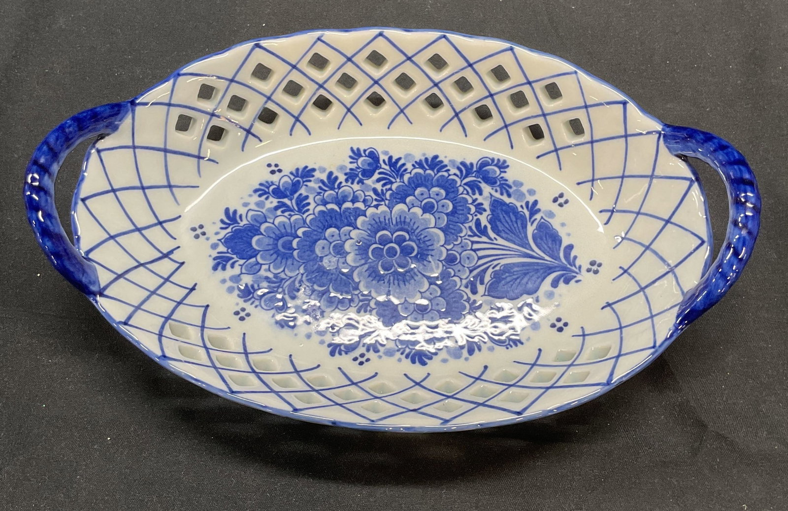 Delft Delfleur Floral Porcelain Basket, Holland: Delft Delfleur porcelain basket in blue with pierced detail and hand painted floral motif. Signed to underside. Made in holland. Measures approx. 7.5 x 5 x 2 inches. Some surface wear consistent with 
