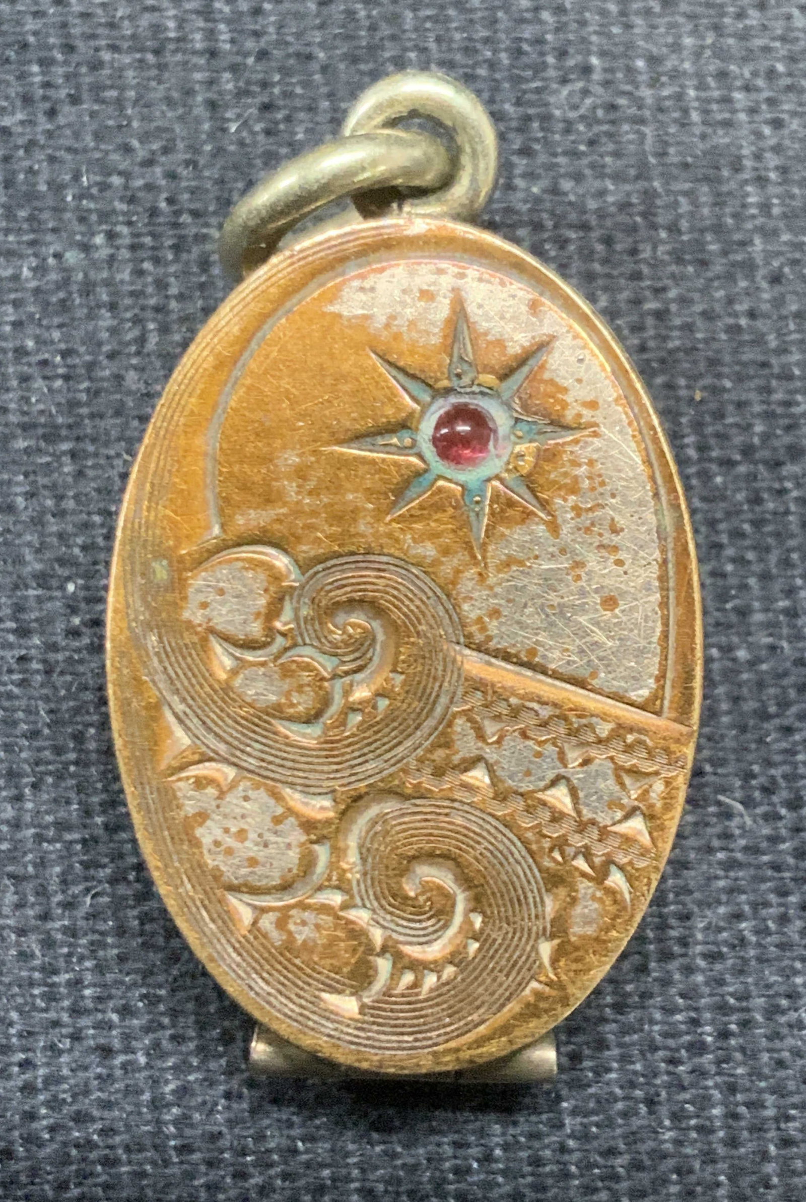 Antique SKM CO Victorian Gold Plated Locket: Antique Victorian era SKM Co gold plated locket with etched case and red cabochon. Signed to interior. Measures approx. 7/8 x 5/8 inches. Some surface wear including scratching and loss to plating obs