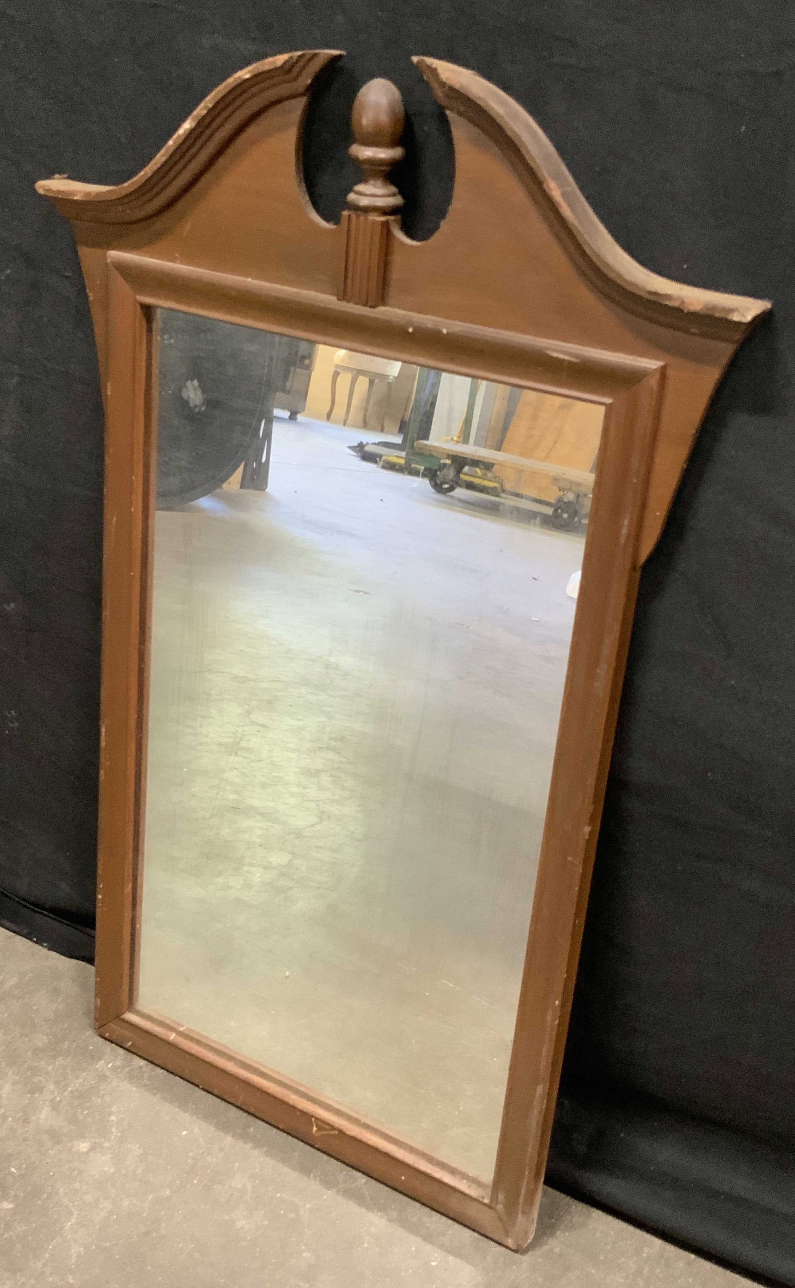 Vintage Wooden Wall Mirror: A vintage wooden mirror with a deep brown hued wood finish. Metal hardware to reverse for display. Measures approx. 17W x 27L in. Some discoloration, separation, chipping, and surface wear present. Vi