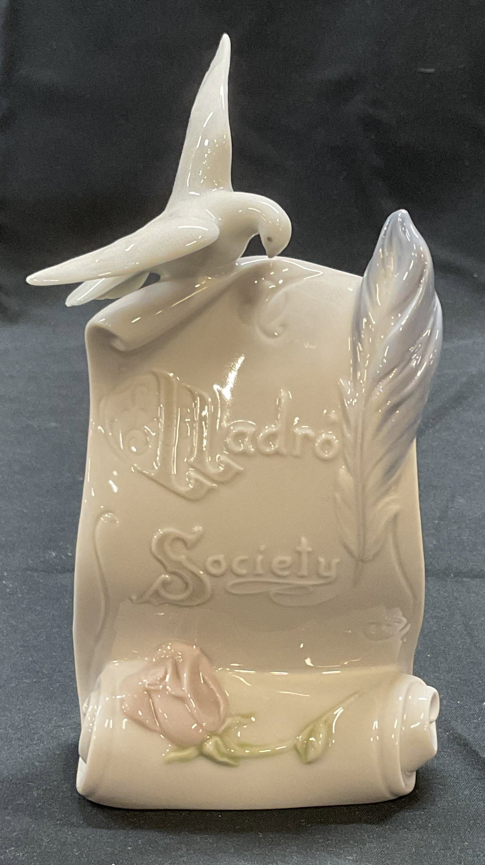 Lladro Society Porcel Dove & Scroll Figural Spain: Lladro Society porcelain figural with dove, quill, rose and scroll motif. Trademarked to underside. Made in Spain. Produced 1998. Measures approx. 3.5 x 2 x 6.5 inches. Some surface wear consistent wi