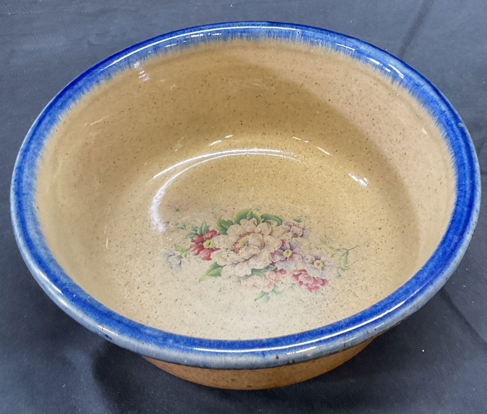 Vintage Stoneware Floral Bowl: Vintage stoneware bowl with floral motif and blue glazed rim. Measures approx. 8.25 x 3 inches. Piece has weight. Some surface wear including scratching observed. Stoneware bowl, floral bowl, vintage