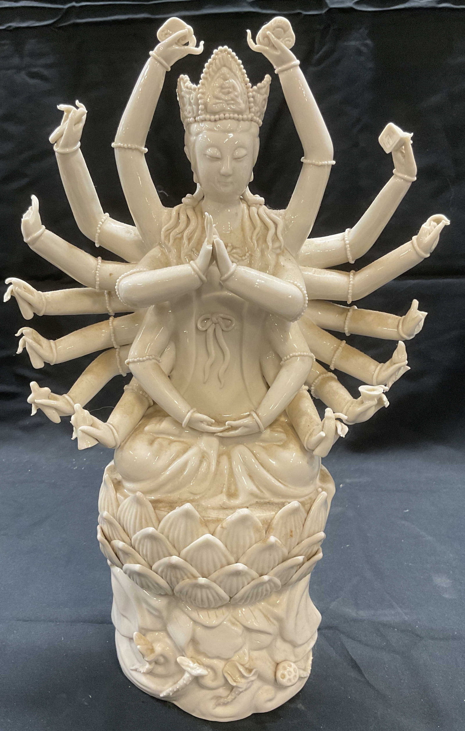 White Porcelain Quan Yin Figural: White porcelain Quan Yin deity figural. Religious figure with many arms in lotus base. Measures approx. 8 x 3 x 14 inches. Marked Facets to interior. Piece has weight, Some surface wear including smal