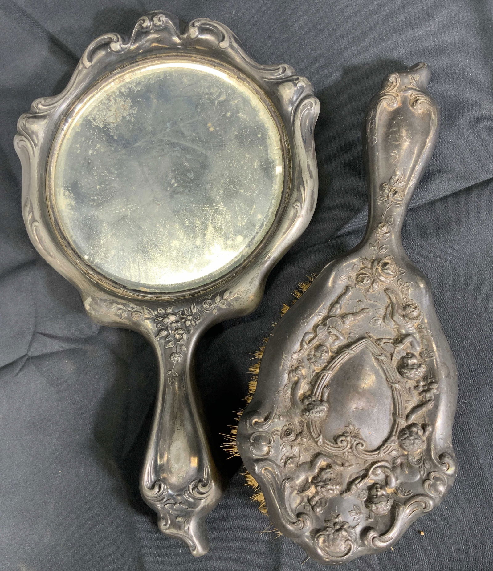 Vintage Art Nouveau Style Hand Mirror & Brush: Metal hand mirror and brush. Art nouveau style frame and handle. Mirror and brush are decorated with scrolling and floral reliefs. Mirror and brush versos have a depiction of a large heart with cherub