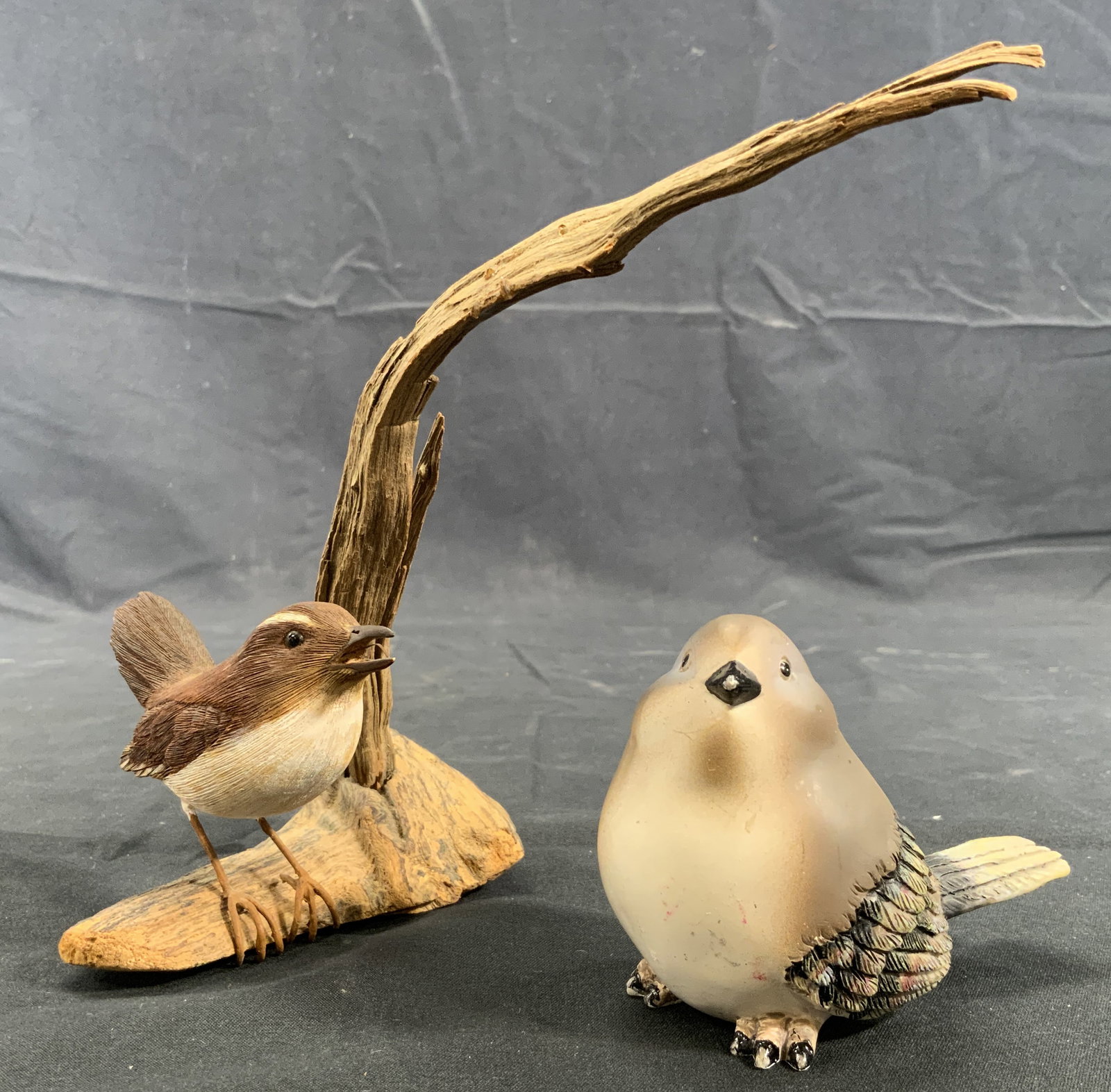2 Lot Composite Birds & Wooden Setting Piece: 2 Composite / wood composite bird figurals. Larger bird measures approx. 4 W x 3 H x 2 D in. Scratches and wear to figurines. Hanging loop on gray bird. Setting piece is two pieces of wood. Setting pi