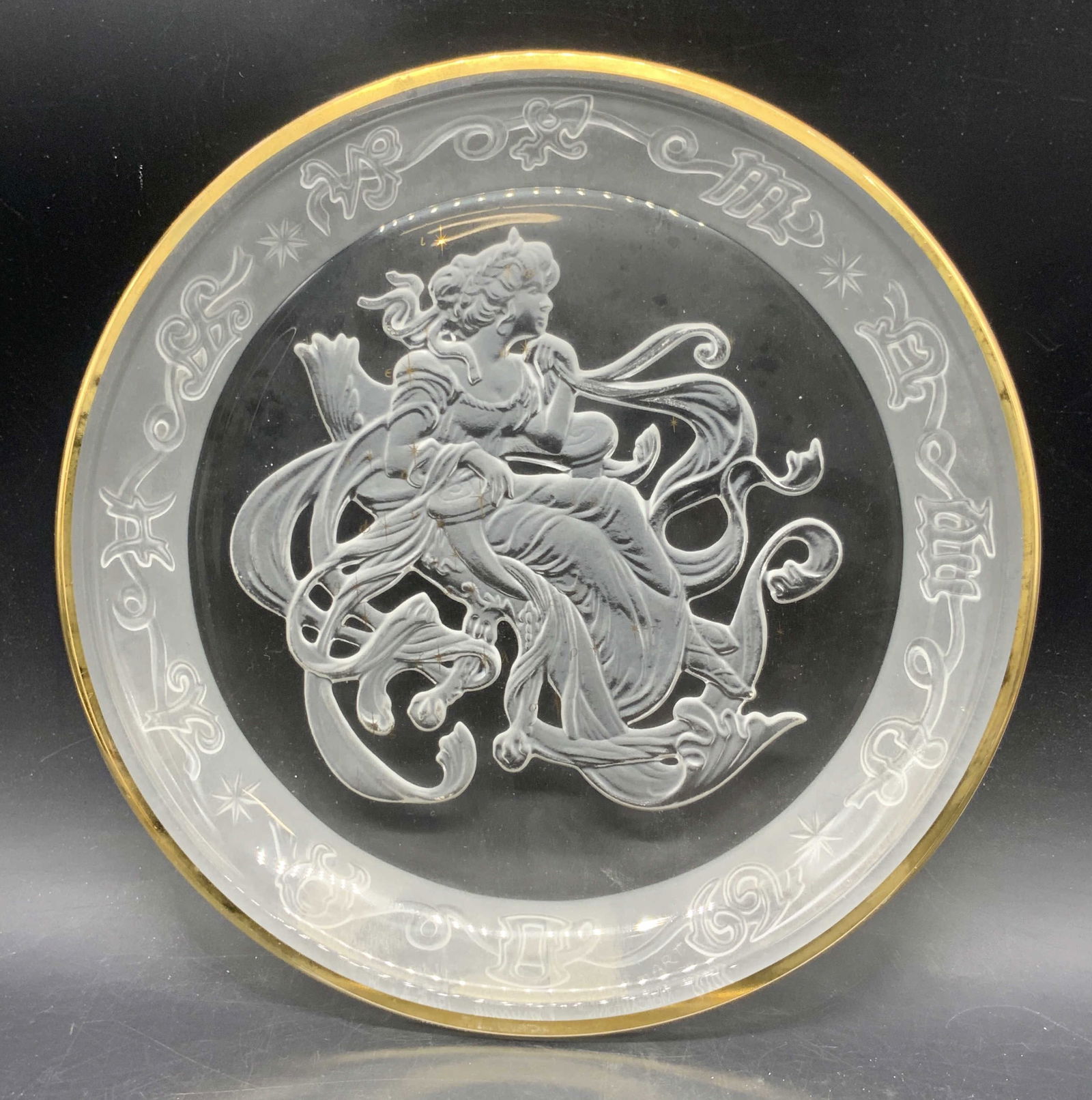 1989 MORGANTOWN CRYSTAL Cassiopeia Crystal Plate: A clear and frosted crystal plate. Gilt accents to the rim and to the obverse of the plate. A woman is depicted in the center surrounded by an astrology motif. Reverse signed EVERHEART, 1989 MORGANTOW