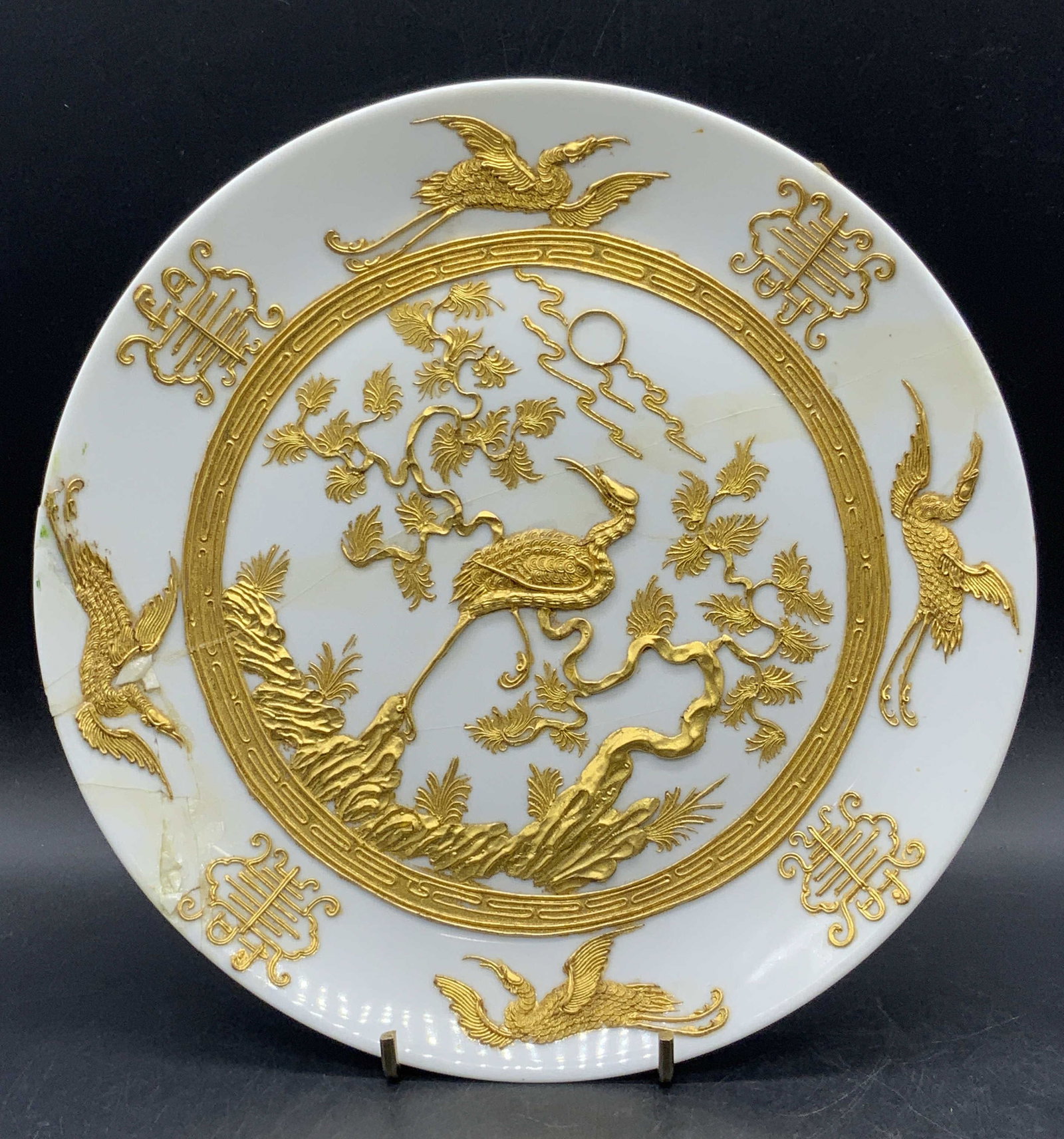 Vintage Asian Porcelain Crane Motif Plate: Vintage Asian Porcelain Crane Motif Plate. Raised gilt designs throughout. Measures approx. 10.25W x 1.25H in. Underside sticker reads MADE IN THE PEOPLES REPUBLIC OF CHINA. Evident repairs and losses