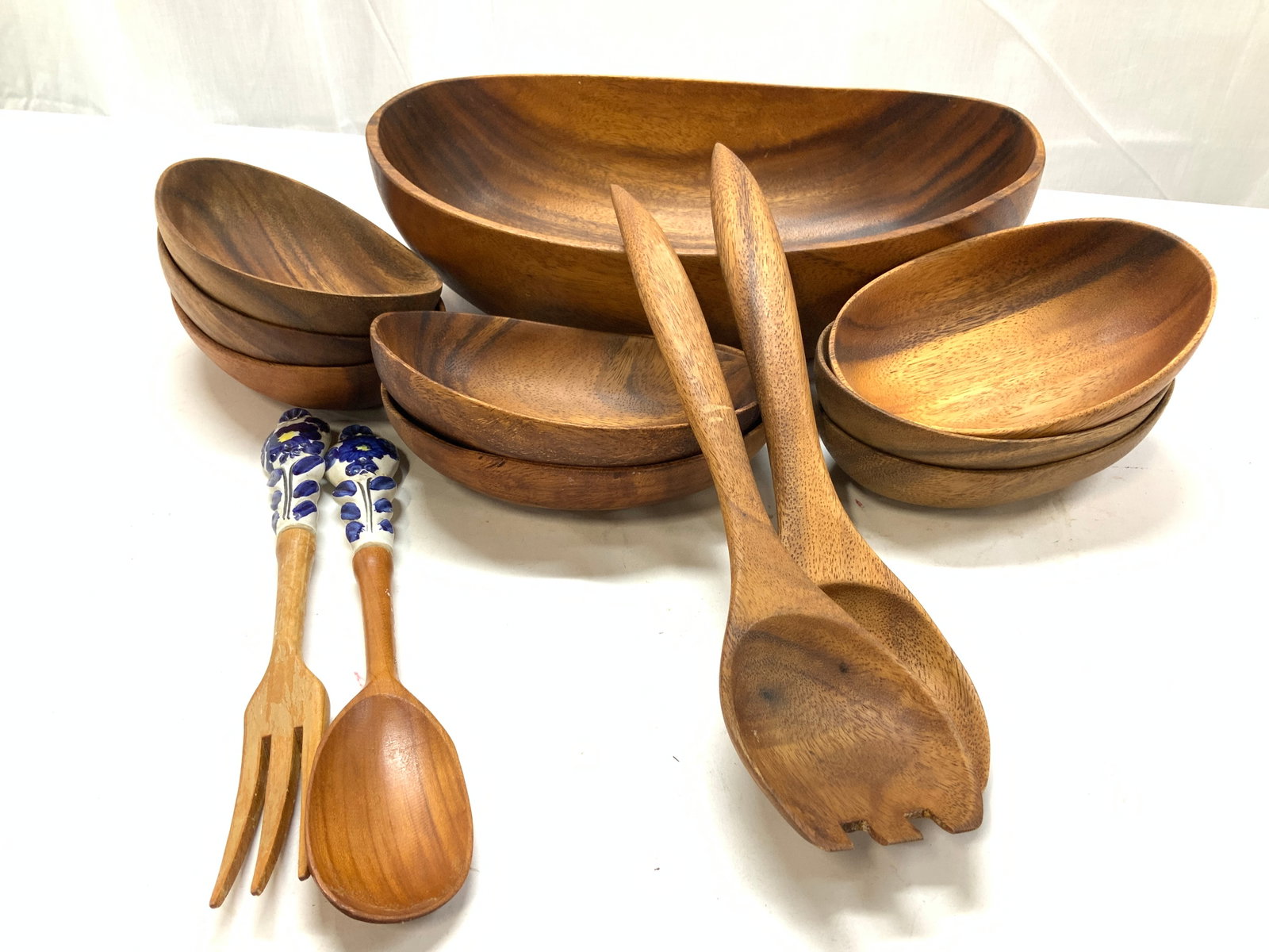 14 Wooden Salad Bowl Set with Utensils: Set 11 wooden salad serving bowl with 8 bowls and pair of salad utensils. Serving bowl measures 13.75 x 9.5 in. Ht is 4 in. Additional pair of salad utensils with ceramic handles. Some mild wear to su