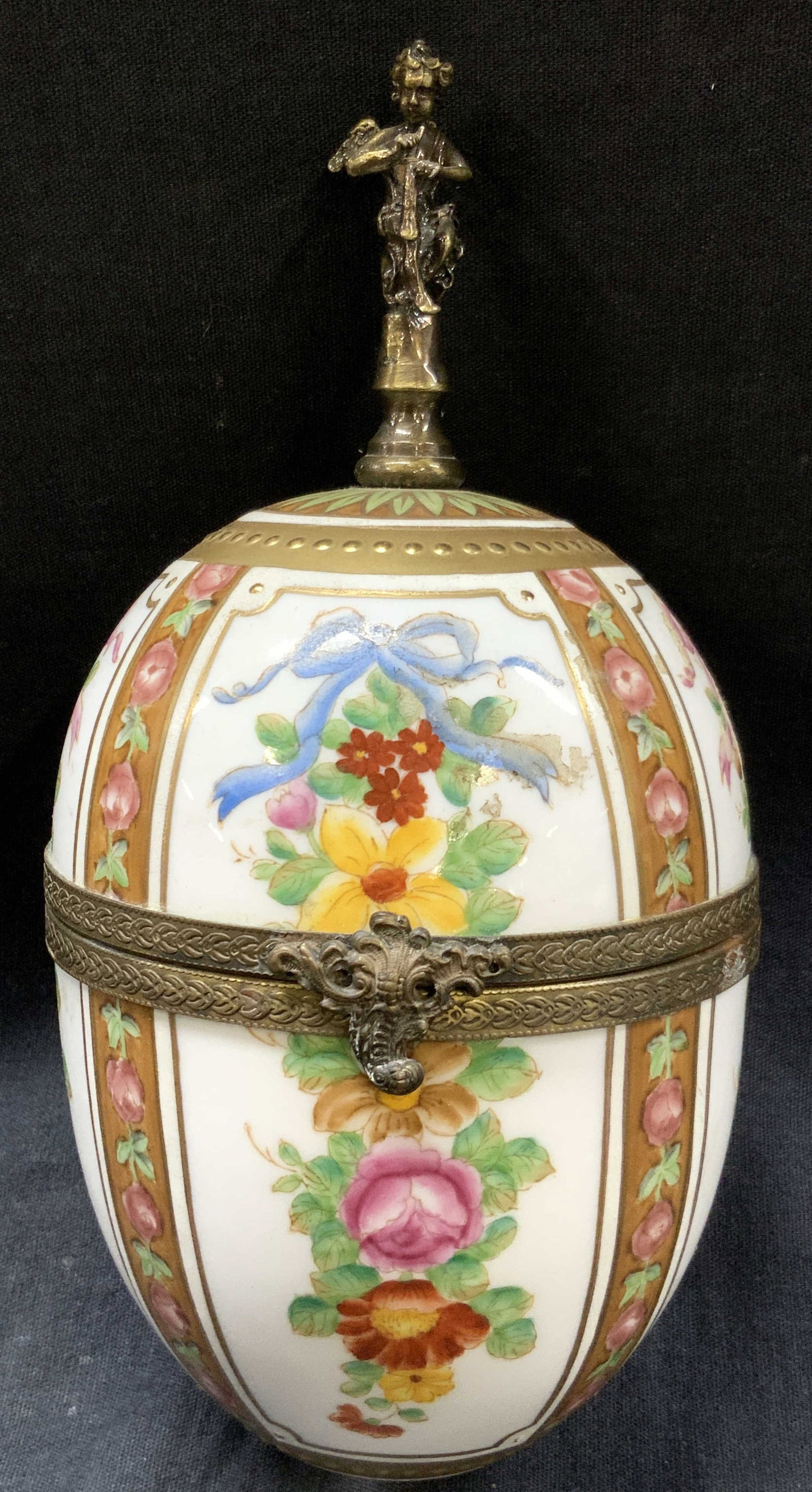 Hand Painter Vntg Porcelain Egg Vessel: Porcelain crafted egg with brass hinged frame and ornament of a cherub on the top. Hand painted with rose and flower motifs with gilt bands and green leaves throughout, approx 8 inches tall and 4 inch