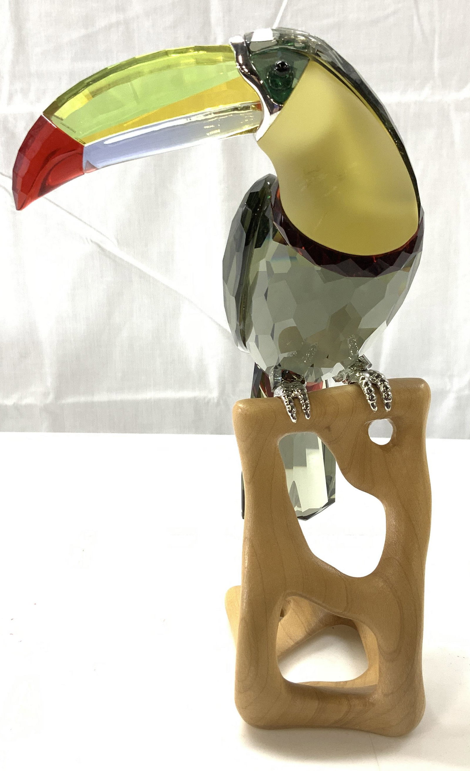 Crystal Toucan Sculpture on Wood Stand: Luxury hand crafted toucan bird, multi faceted crystal. Possibly Austrian crystal . Bird has a smoky colored body with a bright lemon and red beak and red feather. Piece measures 8 x 3 x 5 in. Luxury 