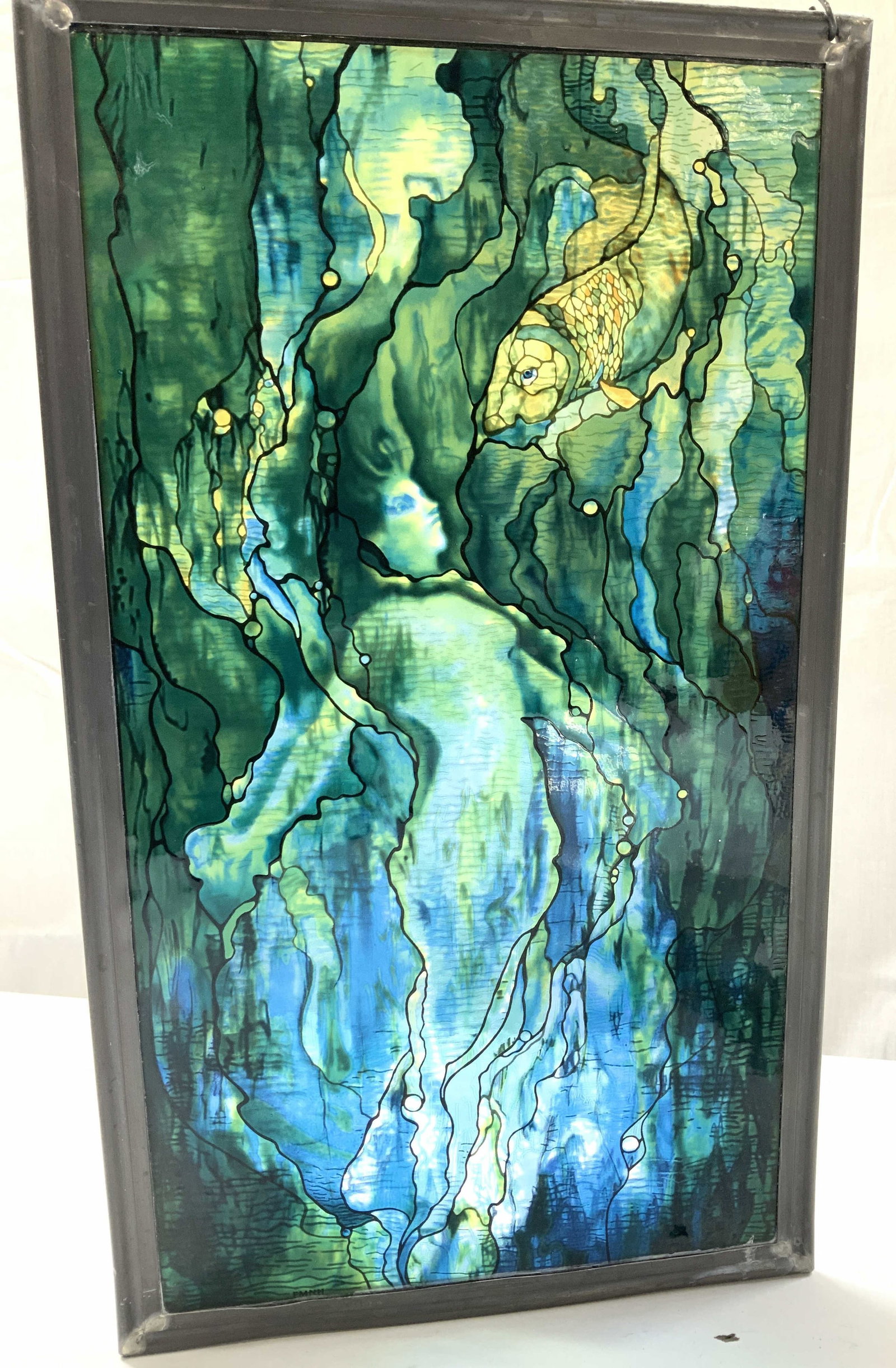 Reproduction Mermaid Glass Panel Louis Comfort Tiffany: Replica of Mermaid with Goldfish by Louis Comfort Tiffany. The initials FMNH are imprinted bottom left for the Field Museum of Natural History. Done in an art nouveau style with cool blues and greens.