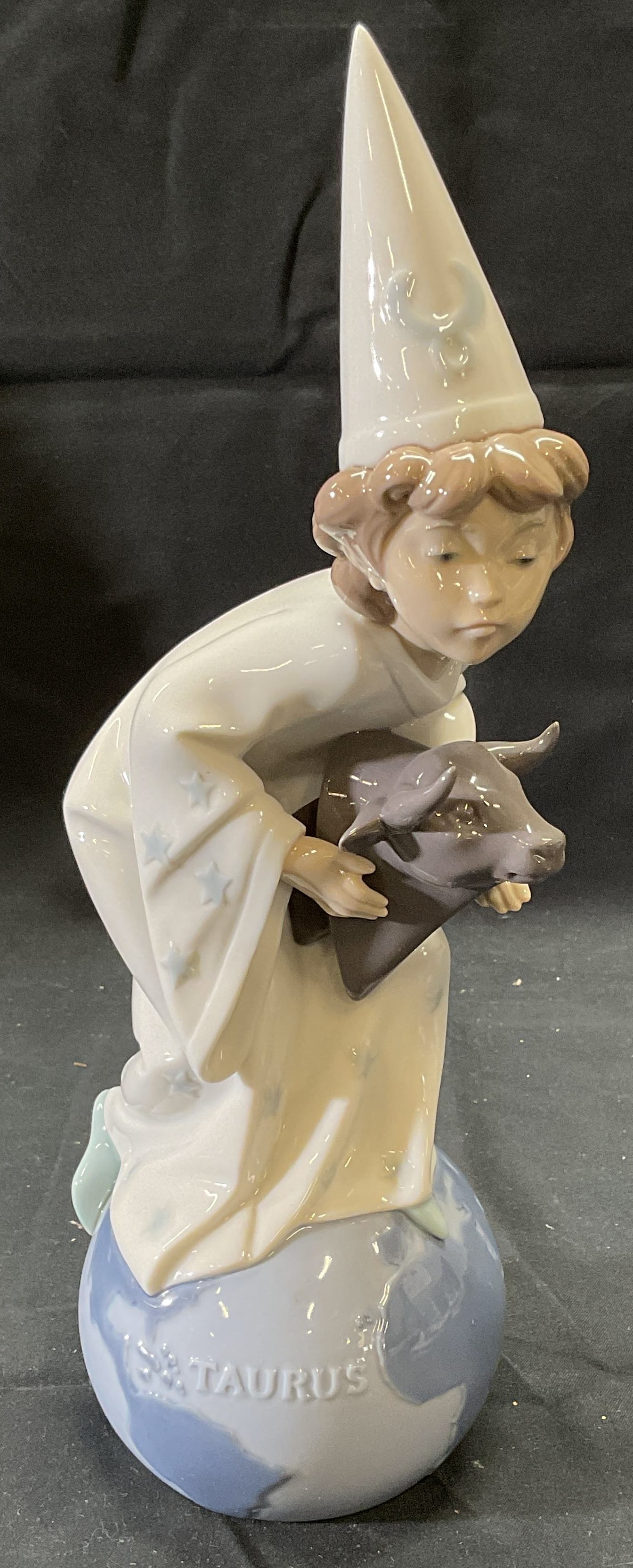 Lladro porcelain Taurus Zodiac Figurine, Spain: Lladro porcelain figurine. Style number 6218. Figure of a child and bull toy on top of globe. Trademarked to underside. Made in Spain. Measures approx. 4 x 10.5 inches. Some surface wear consistent wi