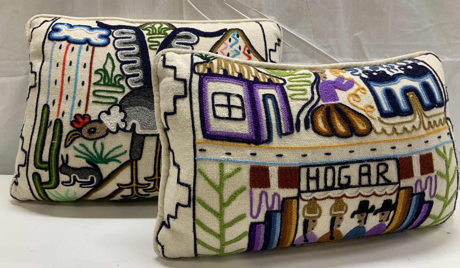 2 Latin American Crewel Feather Pillows: Luxury artisanal toss pillows with vibrant crewel embroidery. Latin American motifs, one pillow reads HOGAR, meaning home in Spanish. The other pillow has a condor bird with mountain and rain cloud on