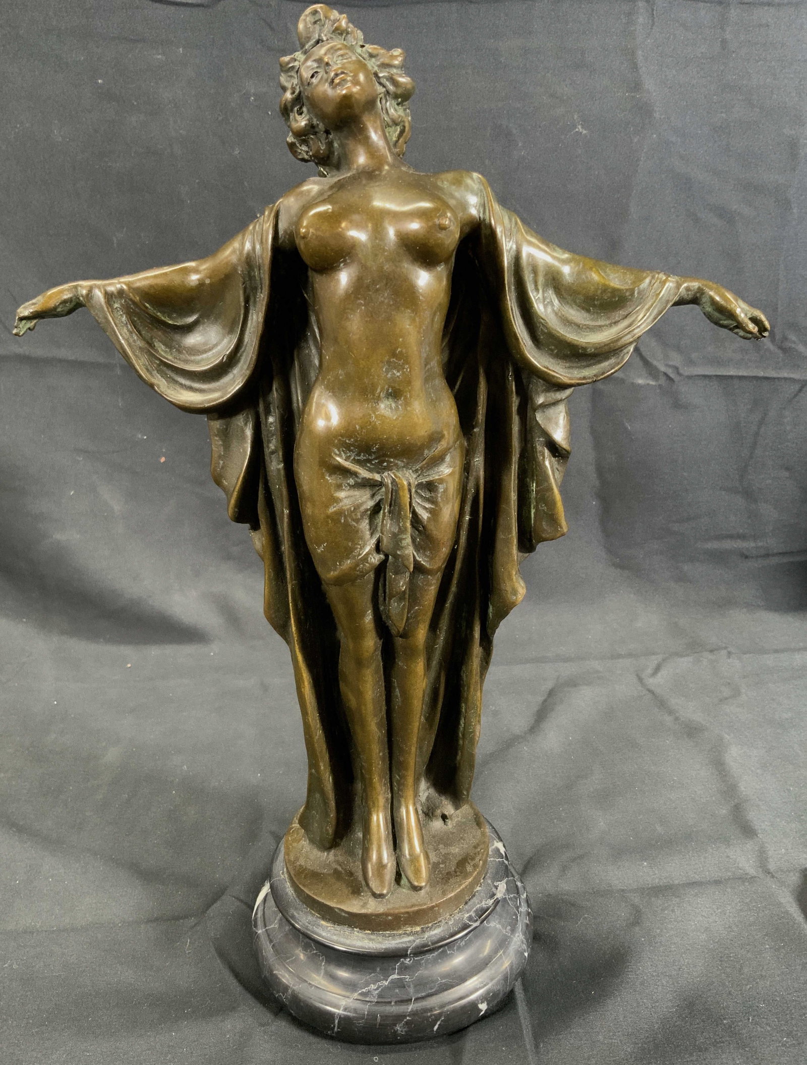 Vintage Bronze Female Nude Statue on Marble Base: Vintage Bronze Statue. Subject depicts a nude woman in a robe with her arms spread to her sides. Base is made of black marble with white veins. Signed in the bronze on left side of bronze base Bosno. 
