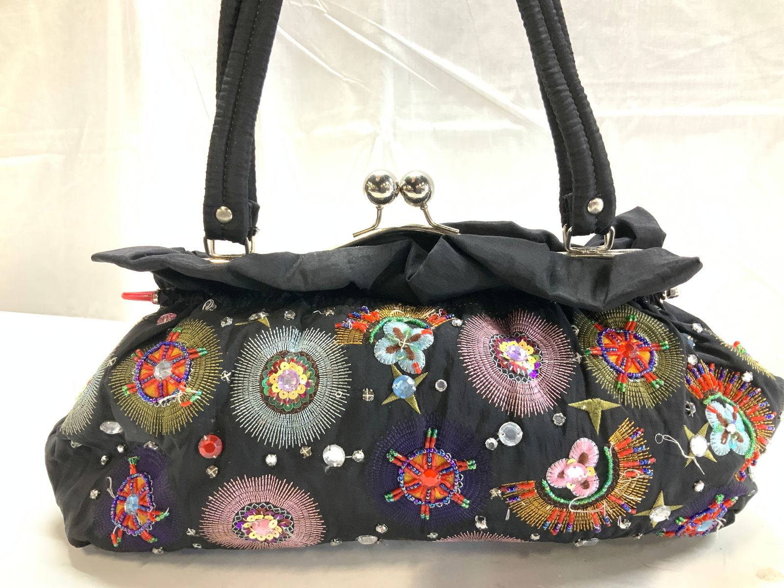 Hand made Kiss Clasp Bead Handbag: Black handbag with front side hand beaded decor, stitching, rhinestones. Large kiss clasp . Handle drop is 9.5 in. Bag measures 15.5 in. Long x 6 in. Wide x 7.5 in. total ht. Opens wide. Some loose st