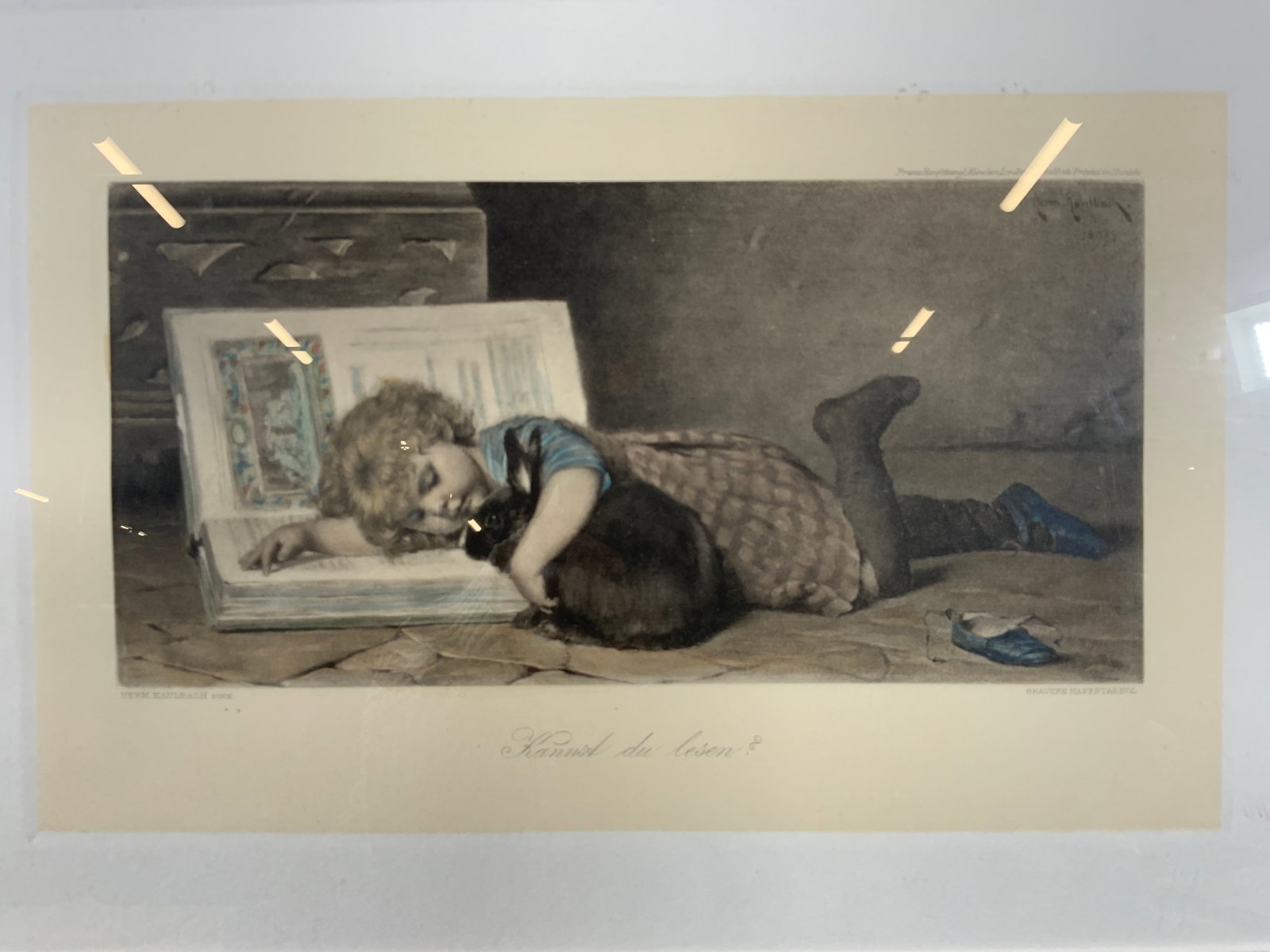 1893 Hermann Kaulbach Kannst Du Lesen? Litho: Lithograph on paper. Signed in type in lower left corner. Artists name Hermann Kaulbach. Caption reads Kannst du Lesen? Right corner reads Gravure Hanfstaengl. Subject depicts a little girl laying on 