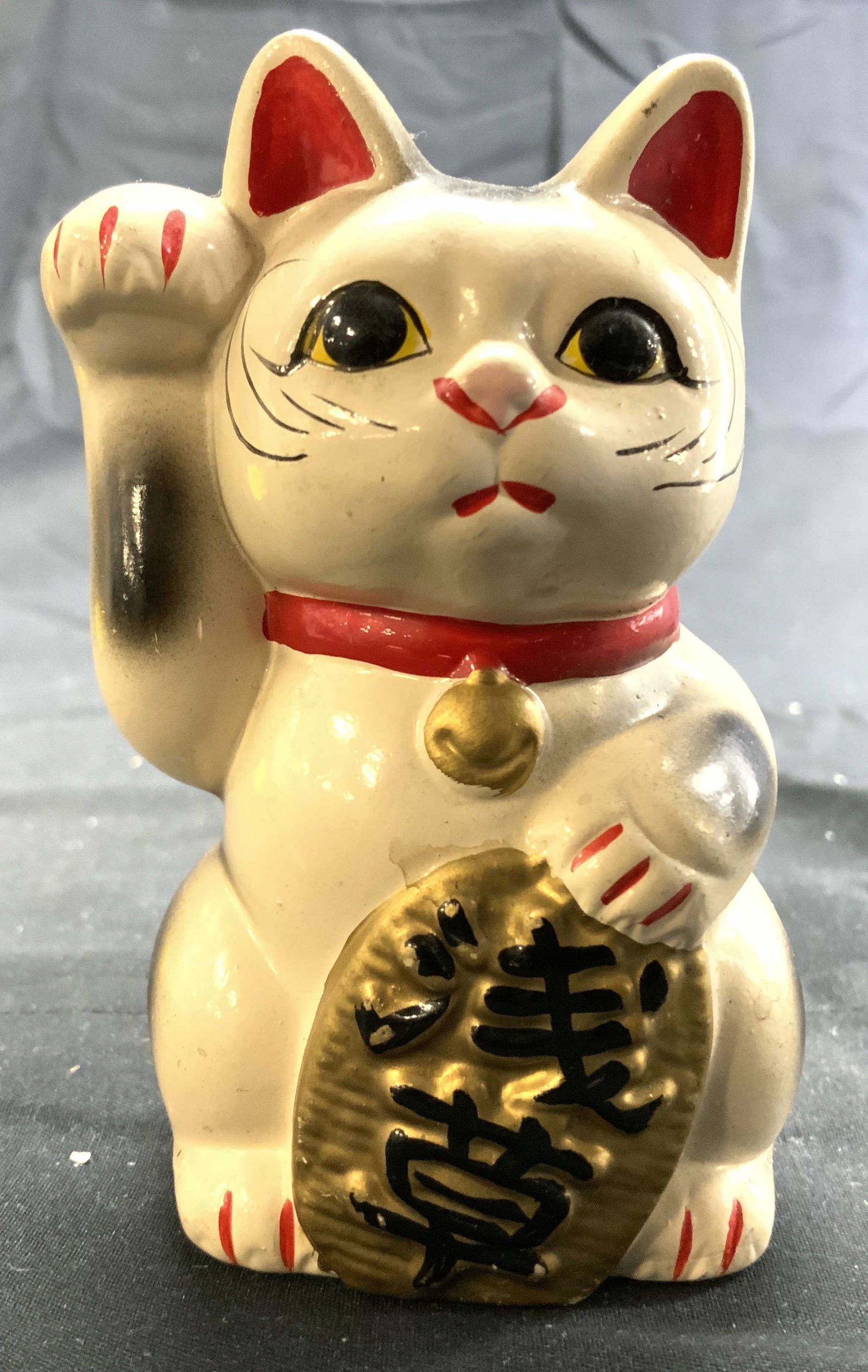 Asian Resinous Cat Fig Coin Bank W Paw Raised: Cat figure coin bank is cream toned. Asian cat figure with paw raised with black toned Asian characters. Piece appears to be crafted from a resinous composite material. Cat figure measures approximate