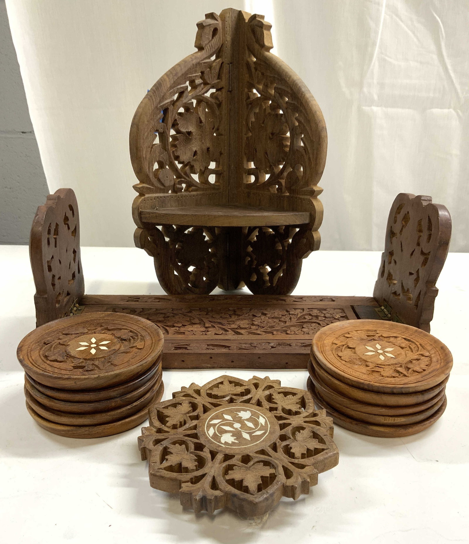 Lot 13 Carved Wooden Moorish Accessories: Lot includes 1 sliding foldable bookend, 1 corner wall shelf, 1 trivet & 10 coasters. Each piece has intricately carved detail. Some pieces have geometric bone inlay. Bookend measures approximately 13