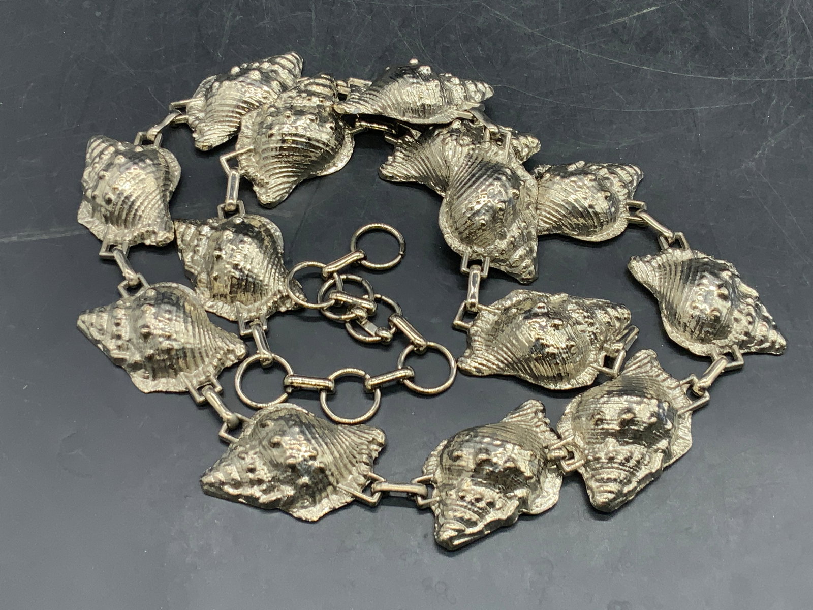 Vintage Silver Tone Metal Shell Belt: A vintage silver tone metal shell belt. Length measured end to end approx. 39 inches. Fishhook clasp closure. Some surface wear consistent with age, use, and exposure. Vintage belts, vintage belt, vin