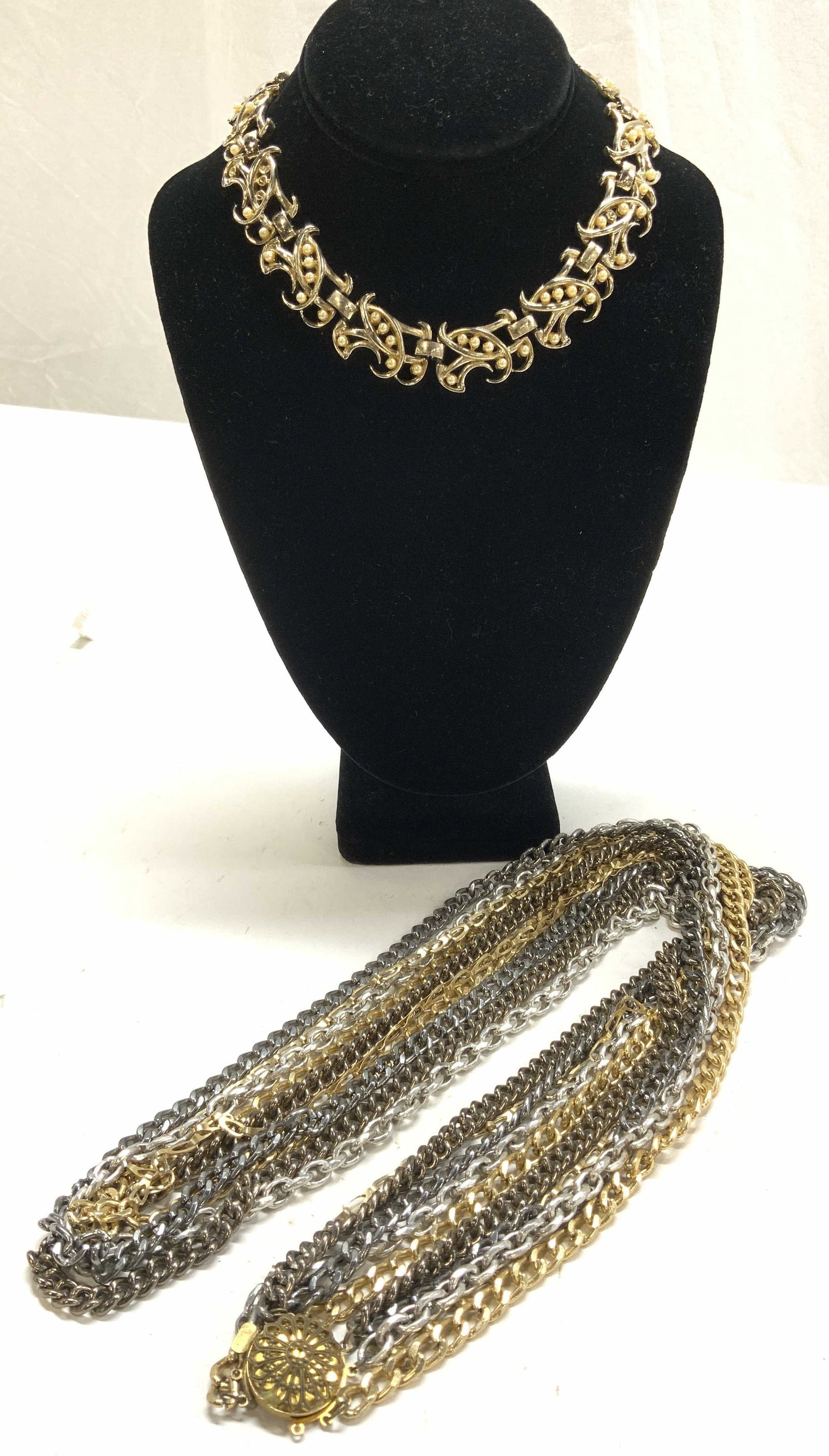 2 Costume Necklaces, Multi- Chain and Choker: Vintage metal costume jewelry. Gold tone choker necklace with faux pearls. 7/8 in. Wide, 15 in. Long. Multi chain rope length necklace. Gold tone, silver tone and gunmetal chains Drop is 19 in. L VINT