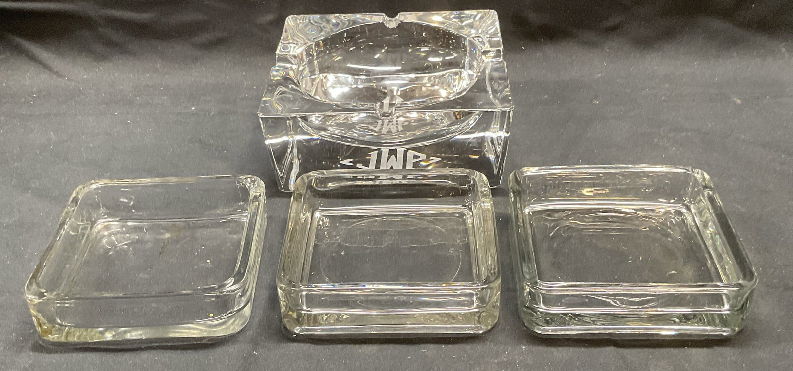 Lot 4 Heavy Crystal Ashtray & Glass Dishes: Lot of 4 pieces. Heavy crystal ashtray with etched monogram on base. Measures approx. 6 x 6 x 2.25 inches. Group of 3 square glass dishes. Measure approx. 4.25 x 4.25 x 1 inches each. All pieces have 