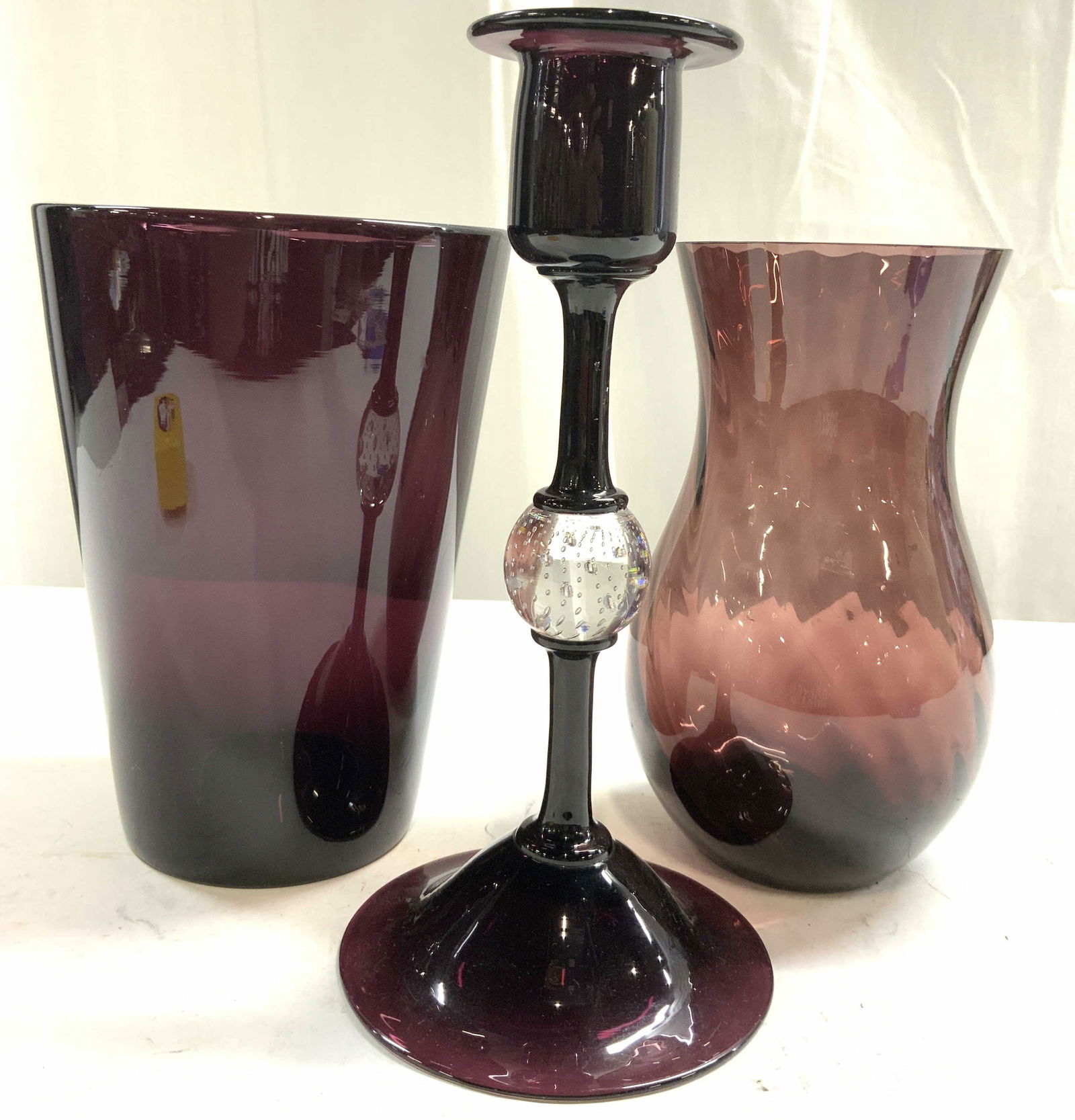 Lot 3 Amethyst Art Glass Vases & Candlestick: Lot includes 1 candlestick, 1 vase with slightly scalloped interior & 1 additional vase. Each piece has various purple tones. Candlestick has spherical form bubble glass area structure in center. Cand