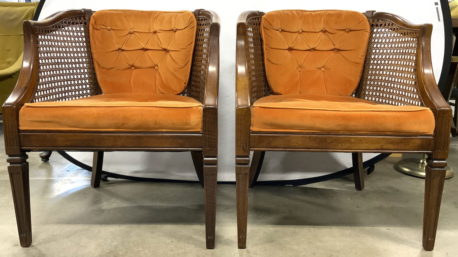 Pr Vntg Mid Century Caned Wooden Barrel Back Chrs: Lot includes 2 chairs. Each are brown toned & wooden possibly walnut. Each chair has barreled back rest with caning. Each have orange toned upholstered cushions. Each cushion is tufted and have weltin