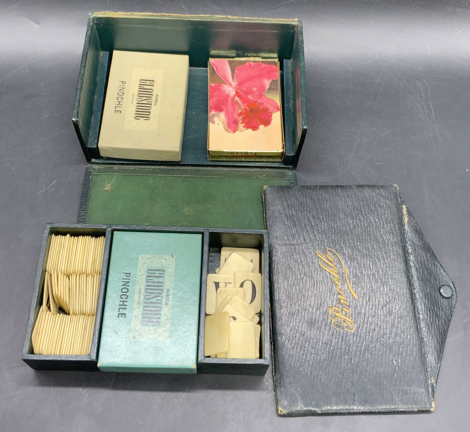 Vintage Pinochle Game Box W/ Cards & Game Pieces: A vintage Pinochle game box crafted from leather and wood. Lid reads Pinochle. Lettered bone tiles and packs of cards to the interior. Some card packs read RUSSEL GLADSTONE, MADE IN USA, PINOCHLE. Som