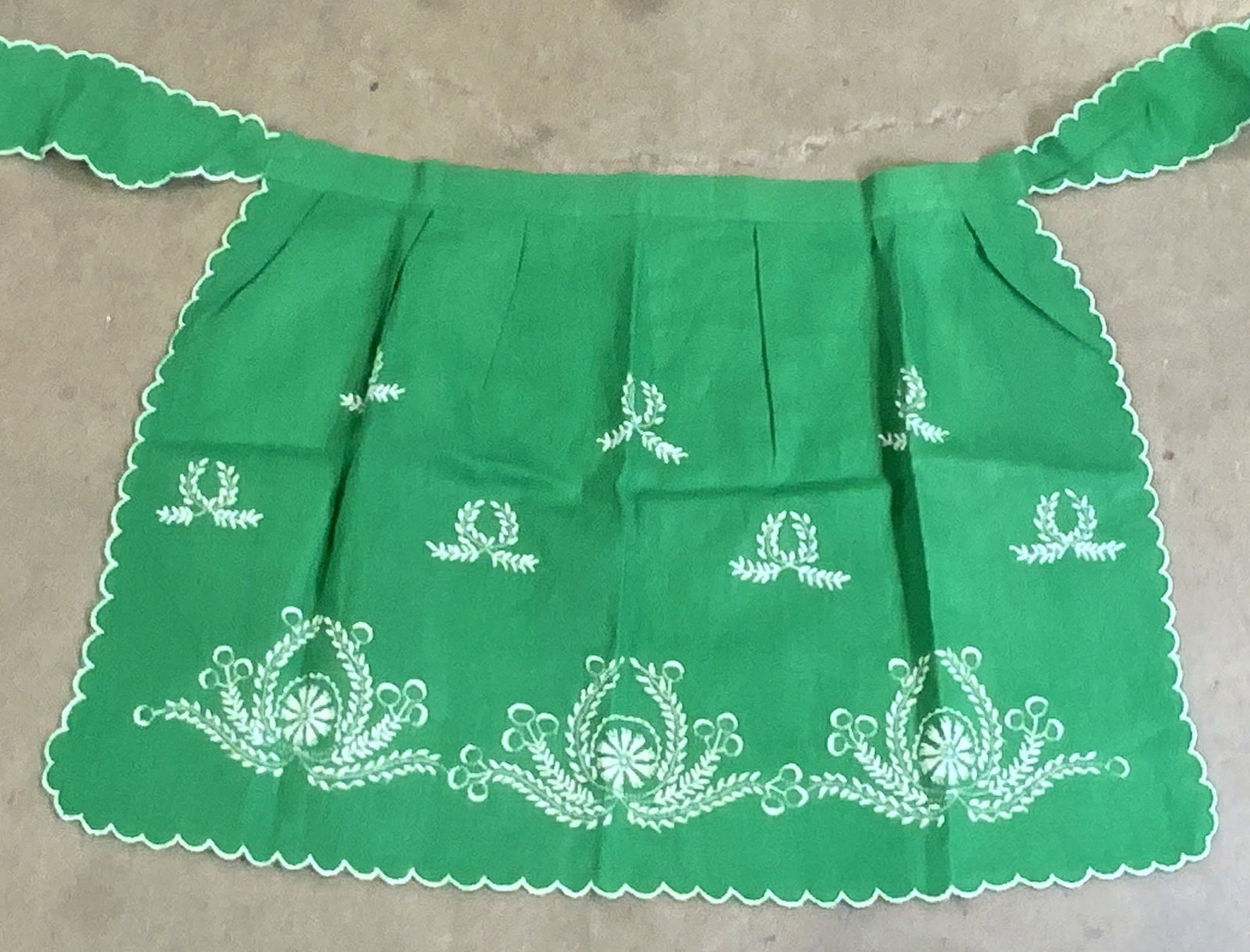 Vintage Green Floral Embroidery Apron: A vintage green apron with white hued floral embroidery. Tie on. Measures approx. 65W x 19L in. Width taken at tie ons measured flat. Wear consistent with age, use, and exposure. Vintage wearables, Vi