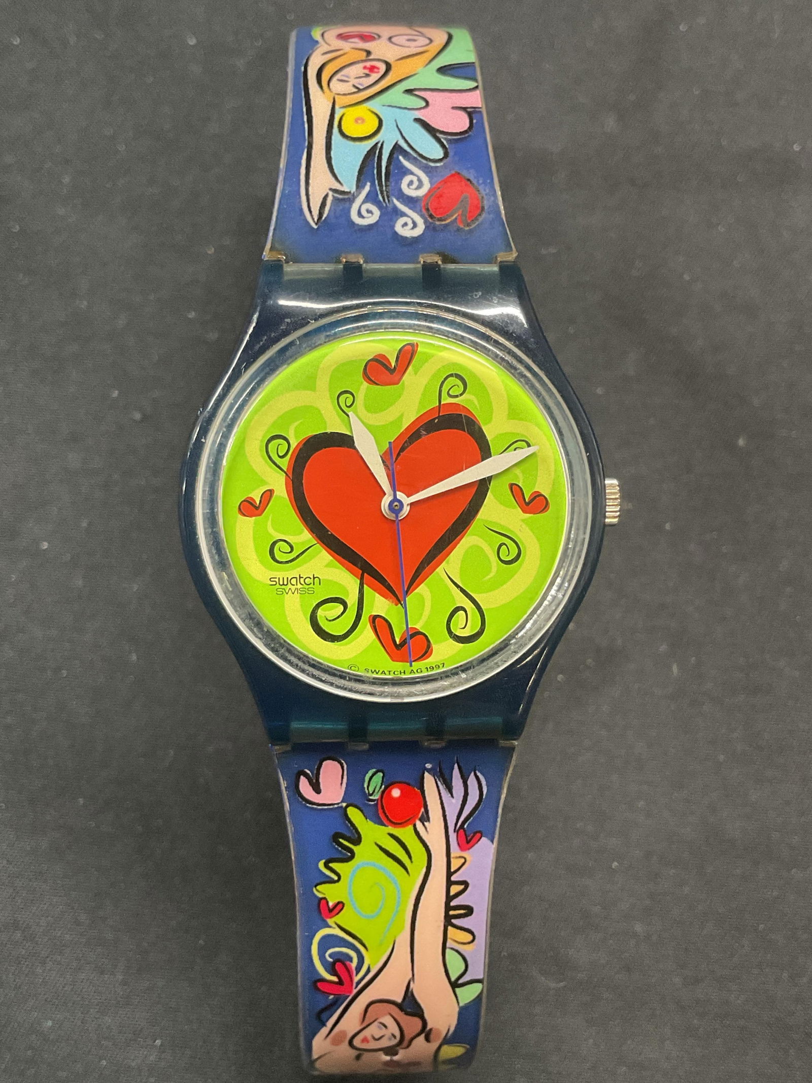 Vintage Swatch Adam & Eve Watch, Switzerland: Vintage 1997 Swatch wrist watch with heart motif on face and Adam and Eve motif in band. Signed on face and band. Measures approx. 8.75 inches long. Not tested for function. Some surface wear includin