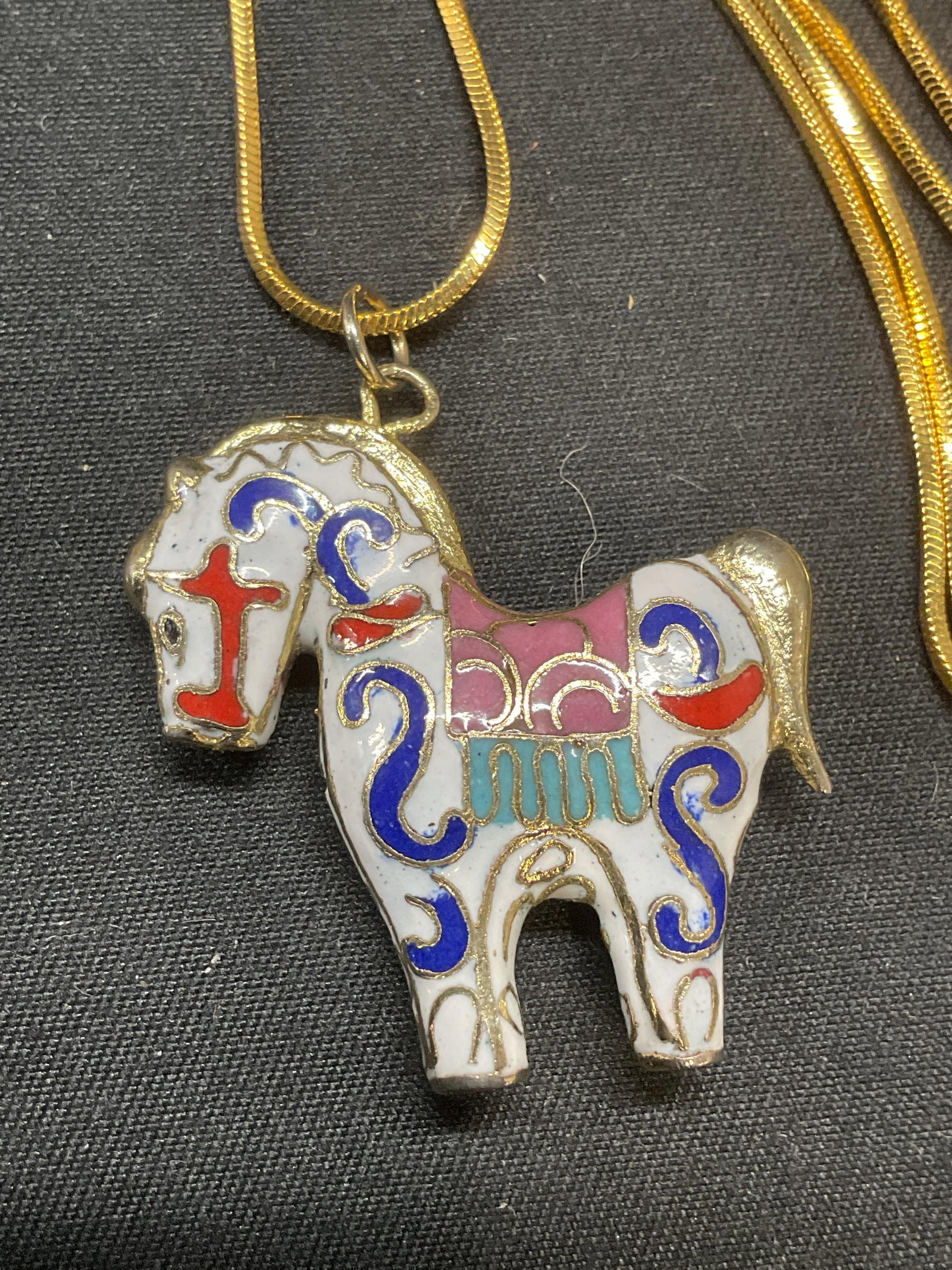 Gold Tone Cloisonne Horse Pendant Necklace: Gold tone chain necklace with white enamel cloisonne horse pendant. Drop length approx. 8.5 inches. Pendant measures approx. 1.25 x 1.25 inches. Some surface wear including scratching observed. Jewelr