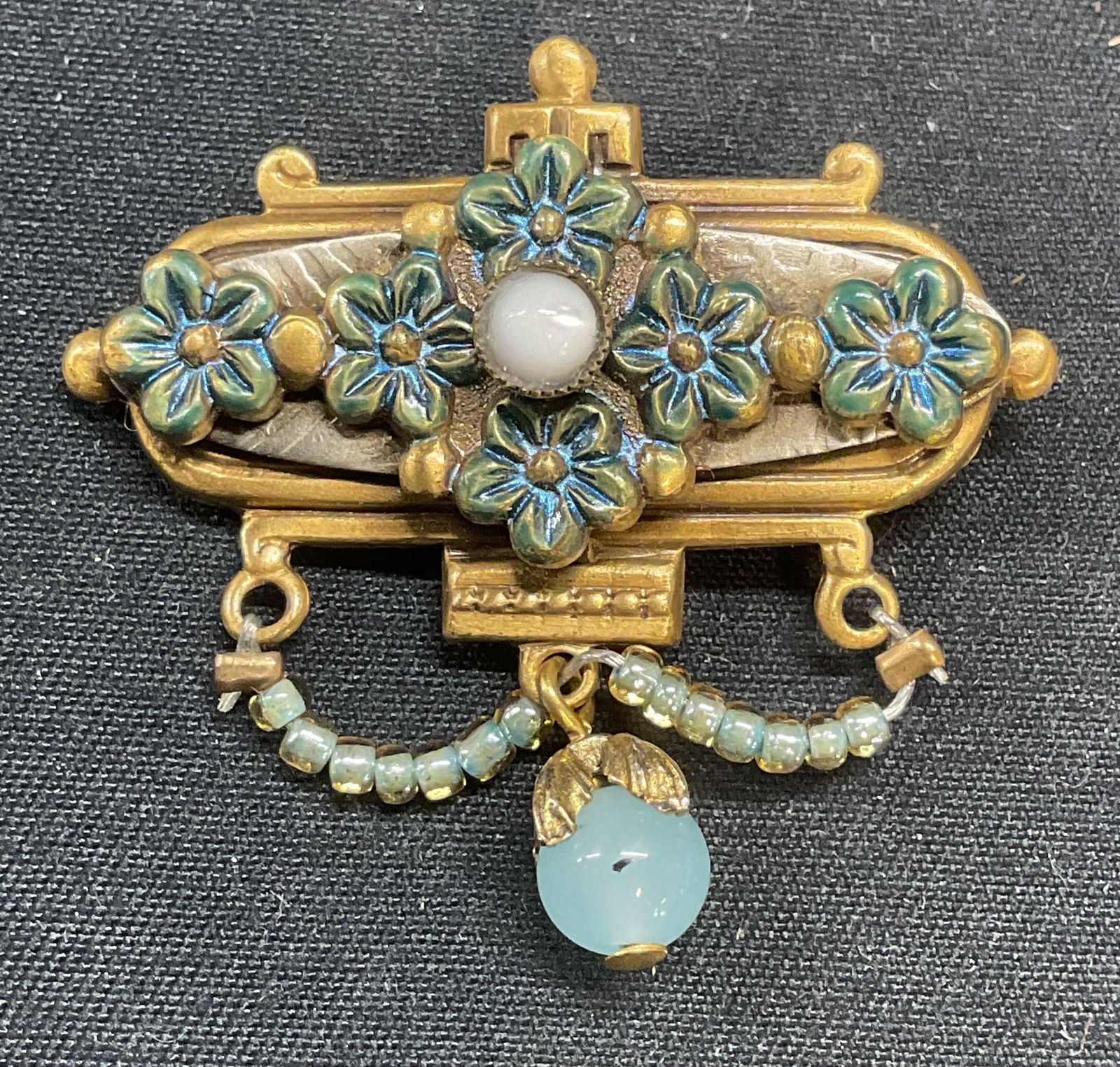 Vintage Gold Tone Blue Flower Beaded Brooch: Vintage gold tone brooch with enameled flower motif and blue beaded decoration. Hinge pin to underside. Measures approx. 1.5 x 1.5 inches. Some surface wear including scratching observed. Jewelry, est
