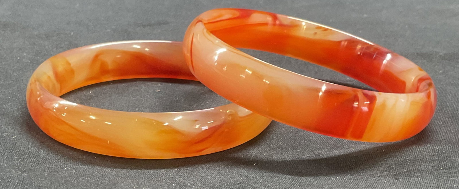 Pair Orange & White Glass Bangle Bracelets: Pair of orange and white toned swirl pattern glass bangle bracelets. Measure approx. 2.5 inches wide. Both pieces have some surface wear including scratching and small chip observed. Includes box. Jew
