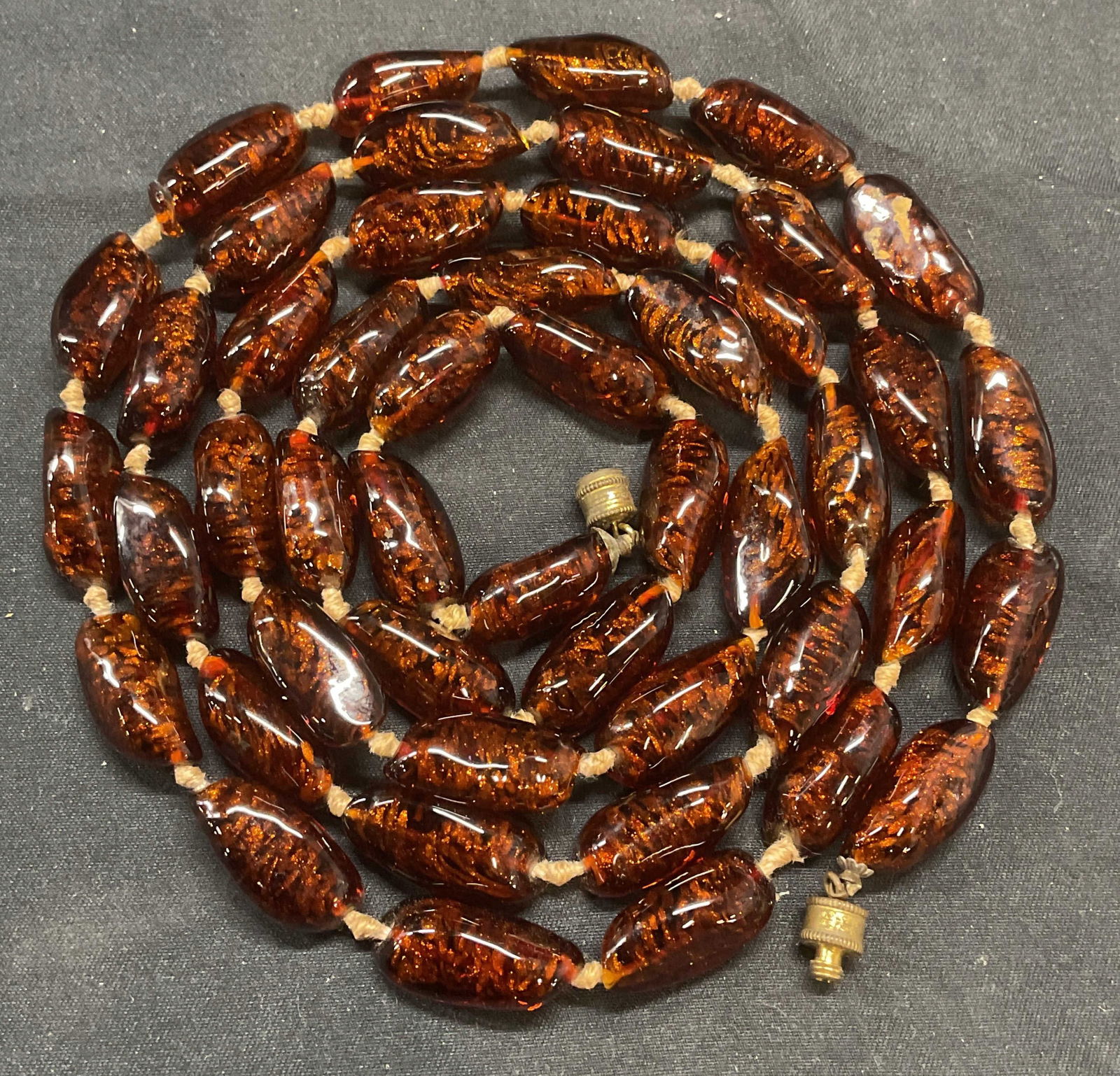 Amber Tone Art Glass Beaded Necklace: Amber toned art glass beaded necklace double knotted string. Necklace has weight. Drop length approx. 23 inches. Some surface wear including scratching observed. Jewelry, fashion jewelry, estate jewel