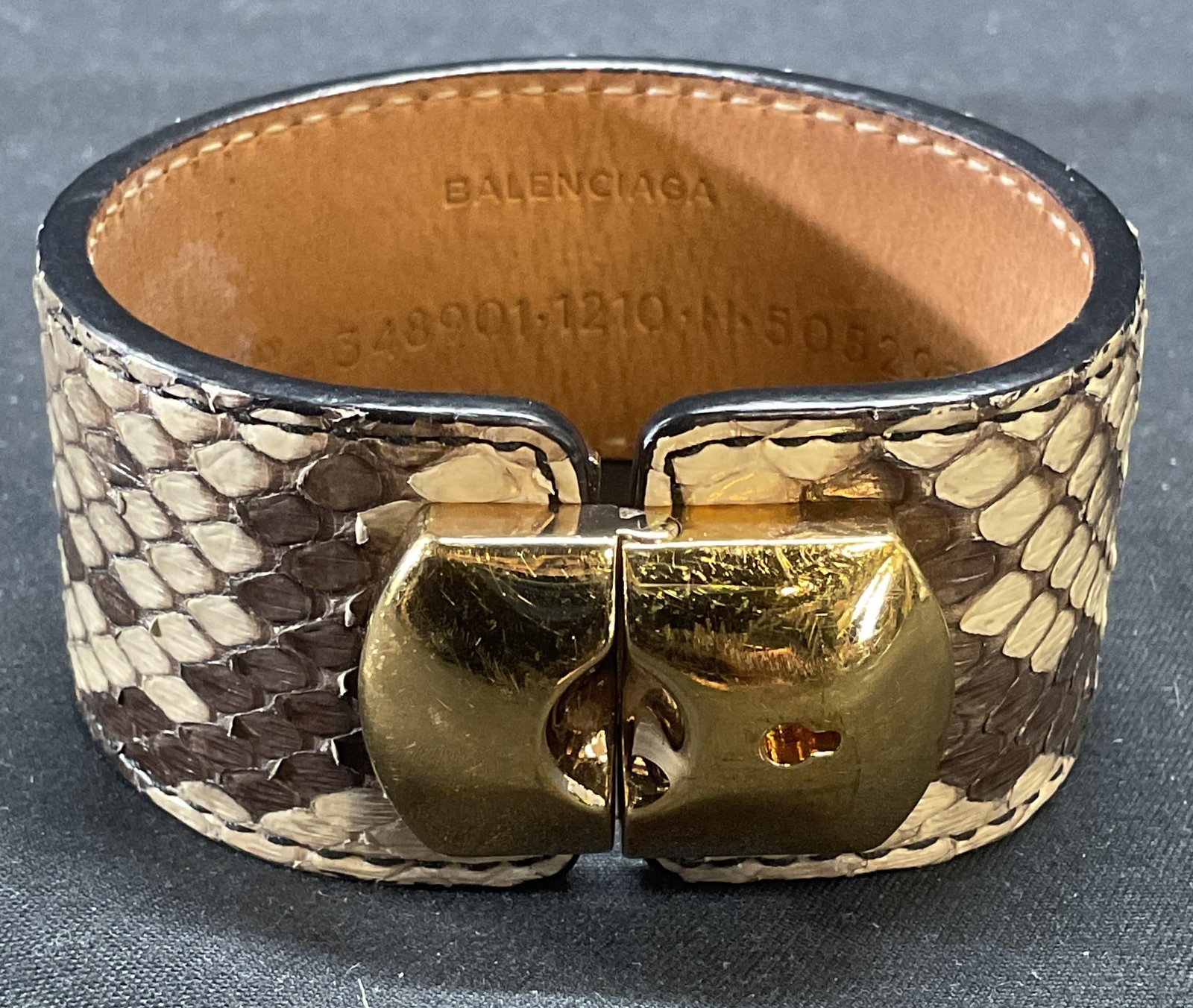 Balenciaga Snakeskin Leather Bracelet, Italy: Balenciaga tan snakeskin leather bracelet with gold tone padlock clasp. Signed on interior. Made in Italy serial number on interior. Measures approx. 7 inches long. Some wear to leather and blemishes 