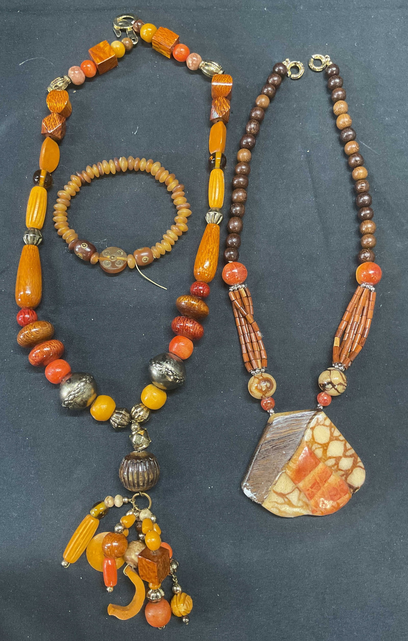 Lot 3 Wood Beaded Pendant Necklace +: Lot of 3 jewelry pieces. Wood beaded pendant necklace with gold tone accents. Drop length approx. 10 inches. Pendant drop approx. 4 inches. Faux wood beaded pendant necklace with stone style resin and