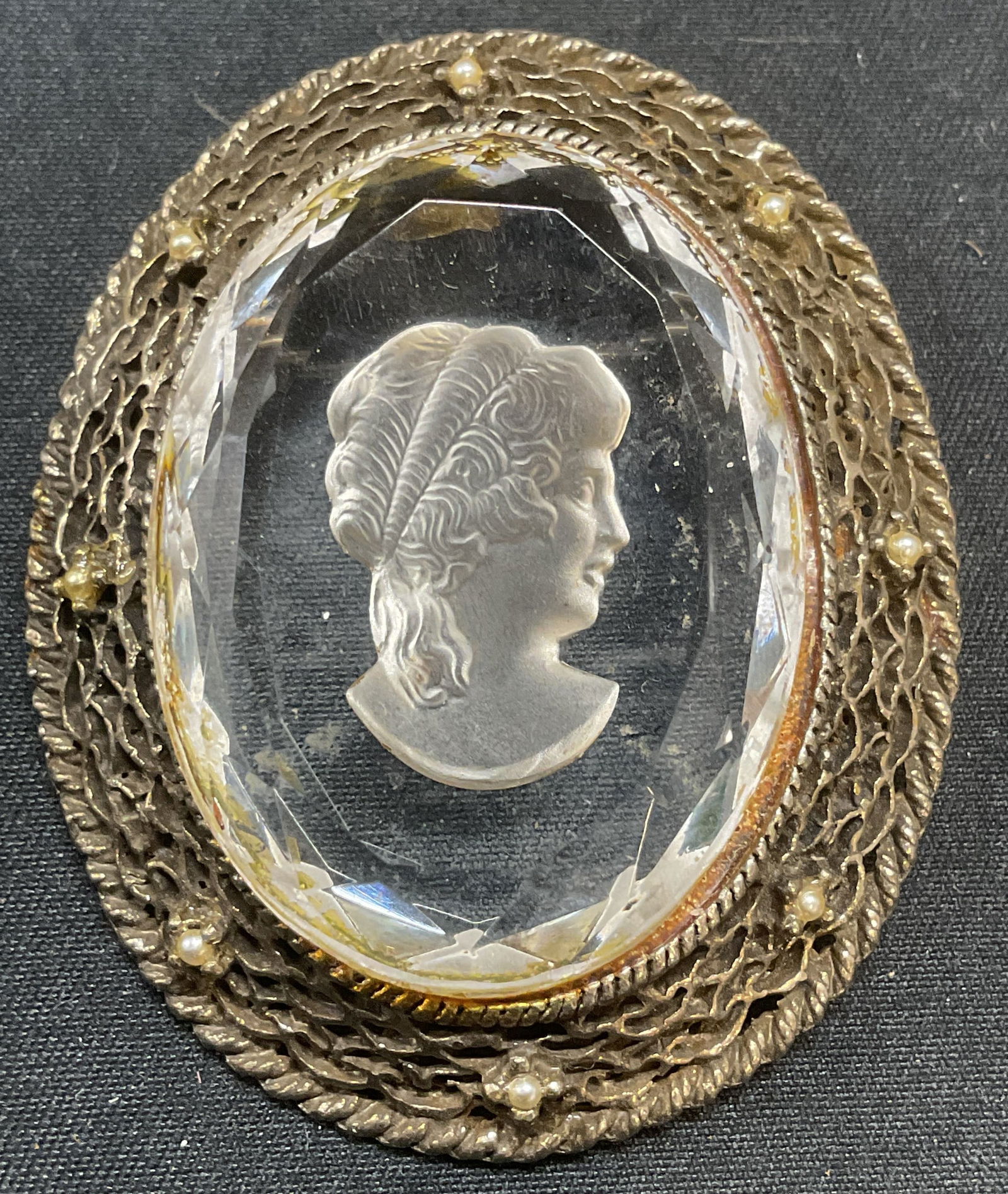 Silver Tone Intaglio Glass Cameo Brooch: Silver tone brooch with intaglio cut glass cameo motif. Faux seed pearl decoration. Hinge pin to underside. Measures approx. 2.25 x 1.75 inches. Some surface wear including scratching observed. Jewelr