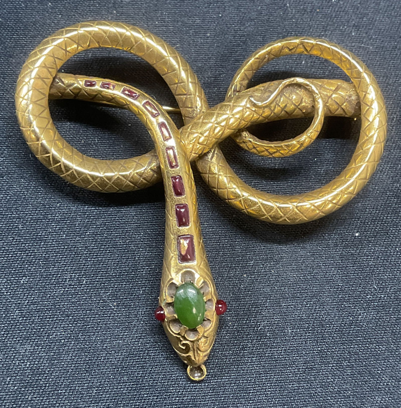 MMA Gold Filled Etruscan Snake Brooch: Metropolitan Museum of Art 1985 gold filled Etruscan snake motif brooch. Jade and ruby cabochon decoration. Signed to underside. Hinge pin to underside. Measures approx. 2 x 2 inches. Some surface wea