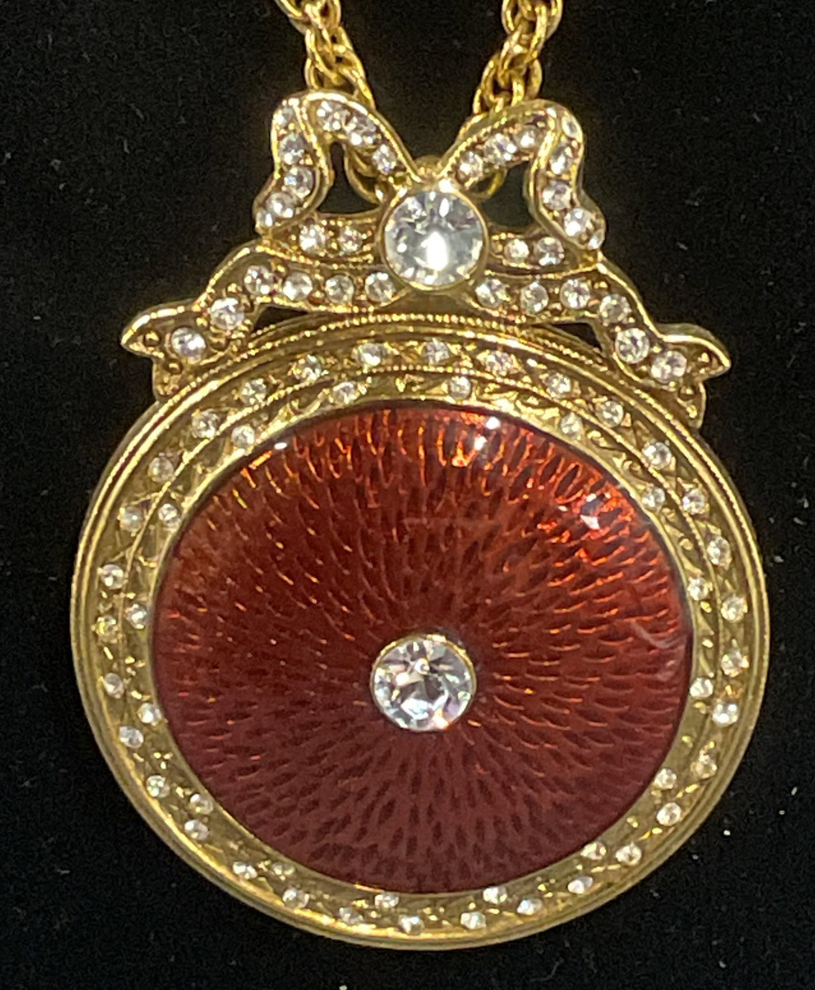 MMA Gold Pl Enamel Crystal Pendant Necklace: Metropolitan Museum of Art gold plated necklace with round enameled red pendant with box motif and colorless crystal decoration. Mirror to reverse of pendant. Signed on hang tag. Drop length approx. 1