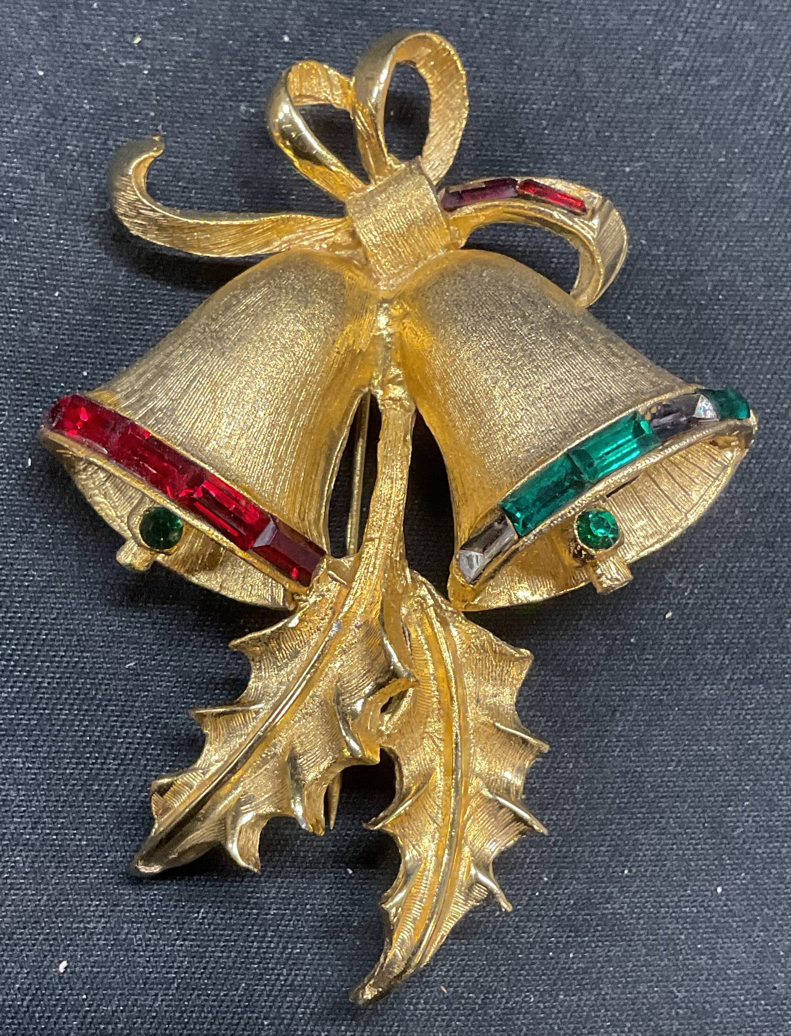 Vtg Pell Gold Tn Christmas Bells & Holly Brooch: Vintage Pell gold tone Christmas bells and holly motif brooch with green and red crystal decoration. Signed to underside. Hinge pin to underside. Measures approx. 2.5 x 2.75 inches. Some surface wear 