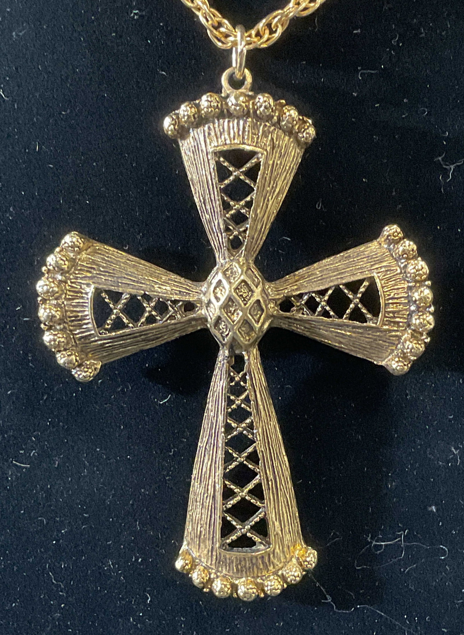 Gold Tone Cross Pendant Necklace on Chain: Gold tone chain necklace with gold tone cross pendant. Pierced and raised bead detail on pendant. Pendant measures approx. 2.75 x 2 inches. Chain drop length approx. 11.5 inches. Some surface wear inc